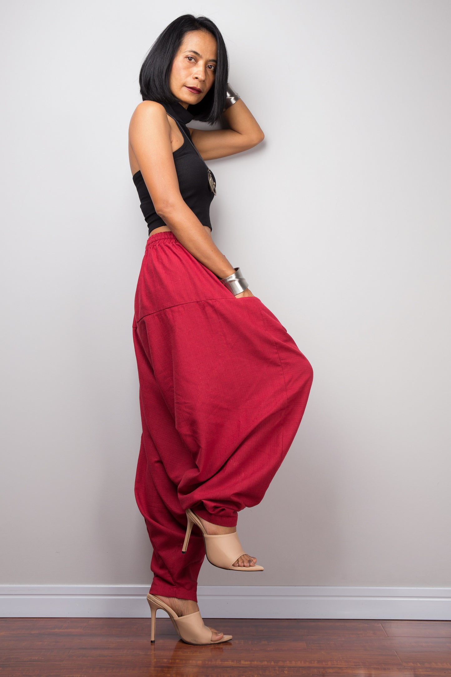 Side view of the red cotton harem pants, displaying the loose fit and the flow of the fabric from the waist to the hem.