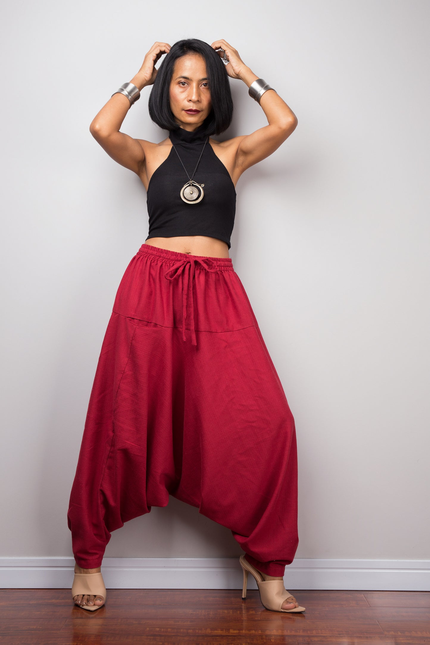 Model wearing red cotton harem pants with a loose fit, standing against a plain background, showcasing the full-length view.