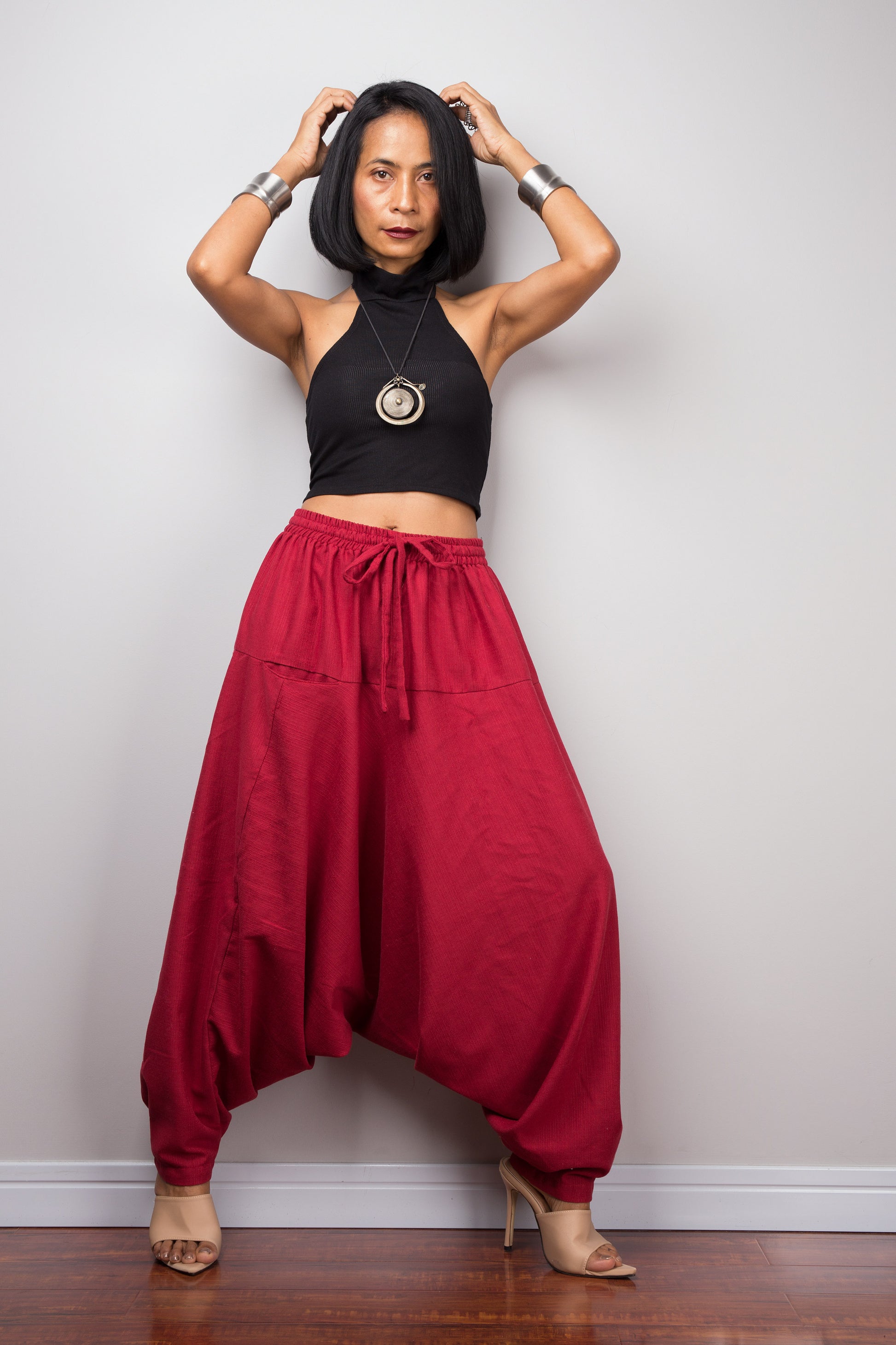 Model wearing red cotton harem pants with a loose fit, standing against a plain background, showcasing the full-length view.