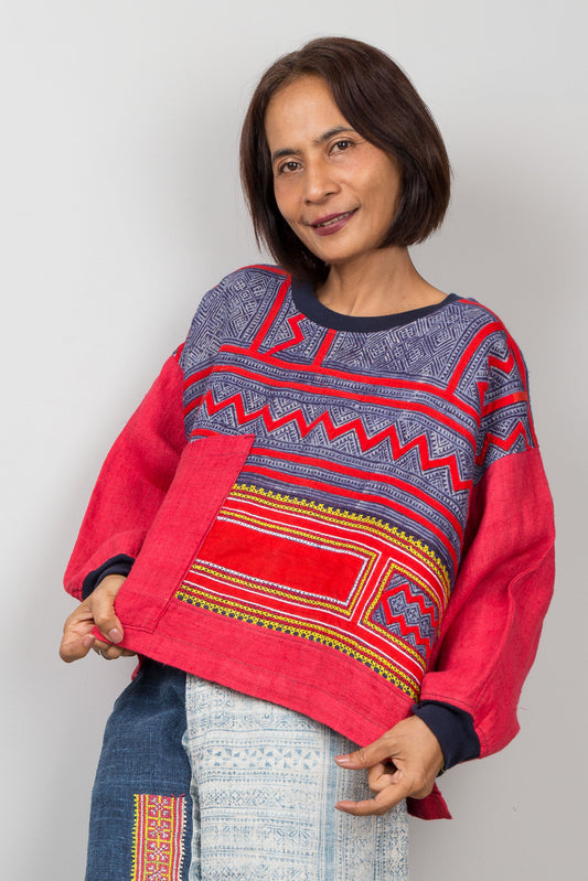 Woman wearing a red and blue patterned hemp sweater against a plain background
