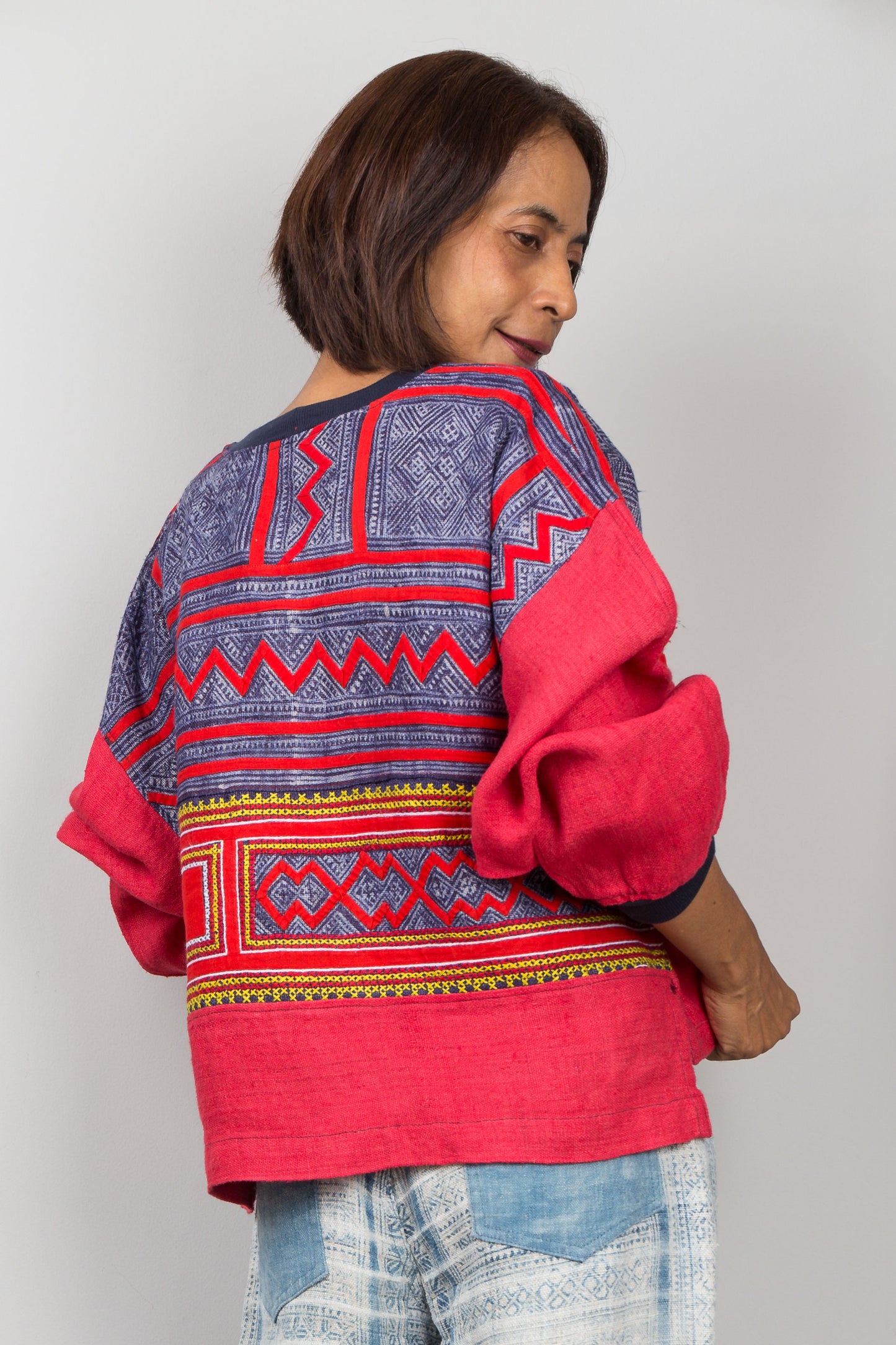 Person wearing a red and blue patterned top against a plain background