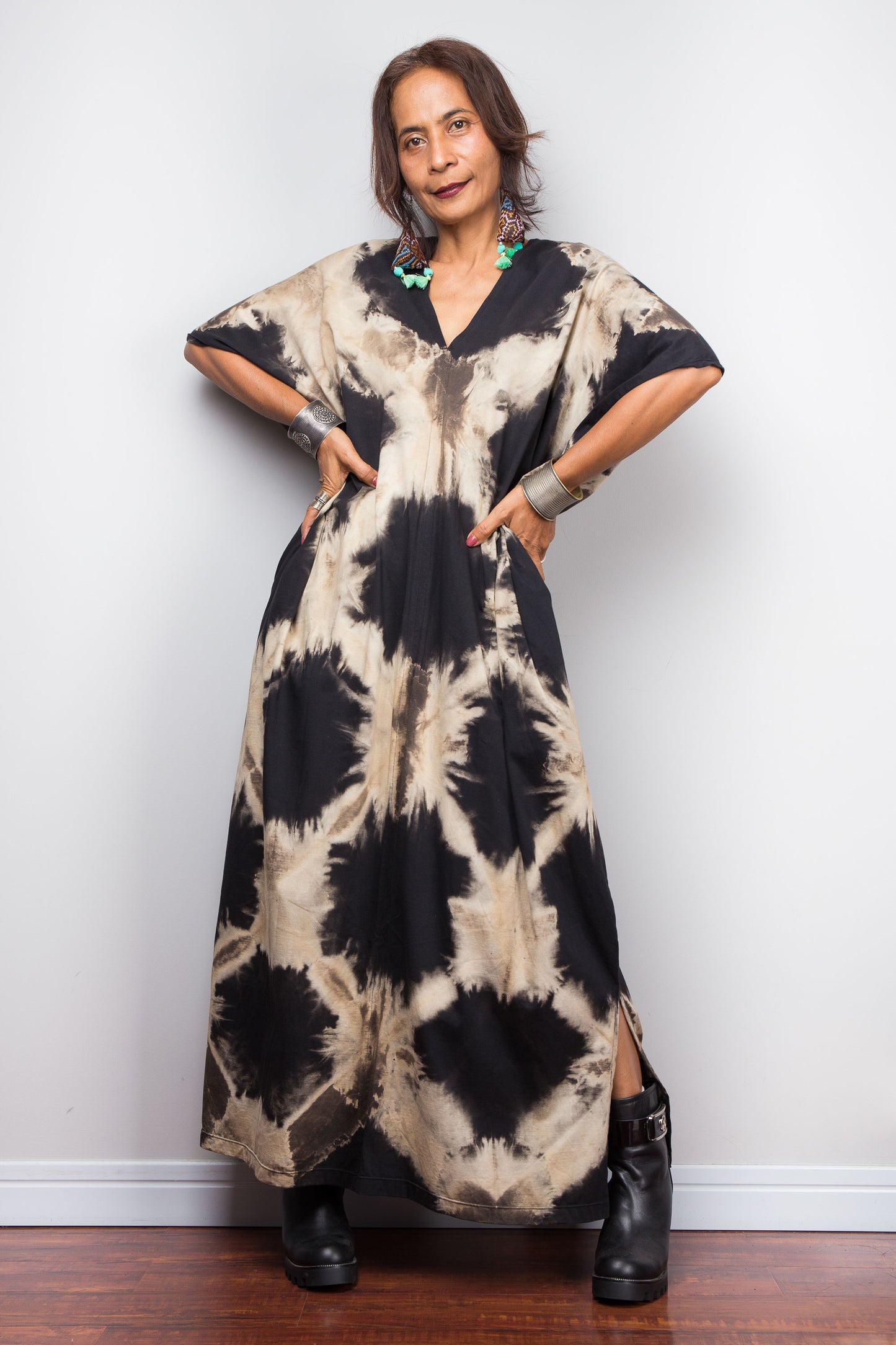Woman wearing an original Nuichan brand, reverse tie dye kaftan dress against a grey wall.