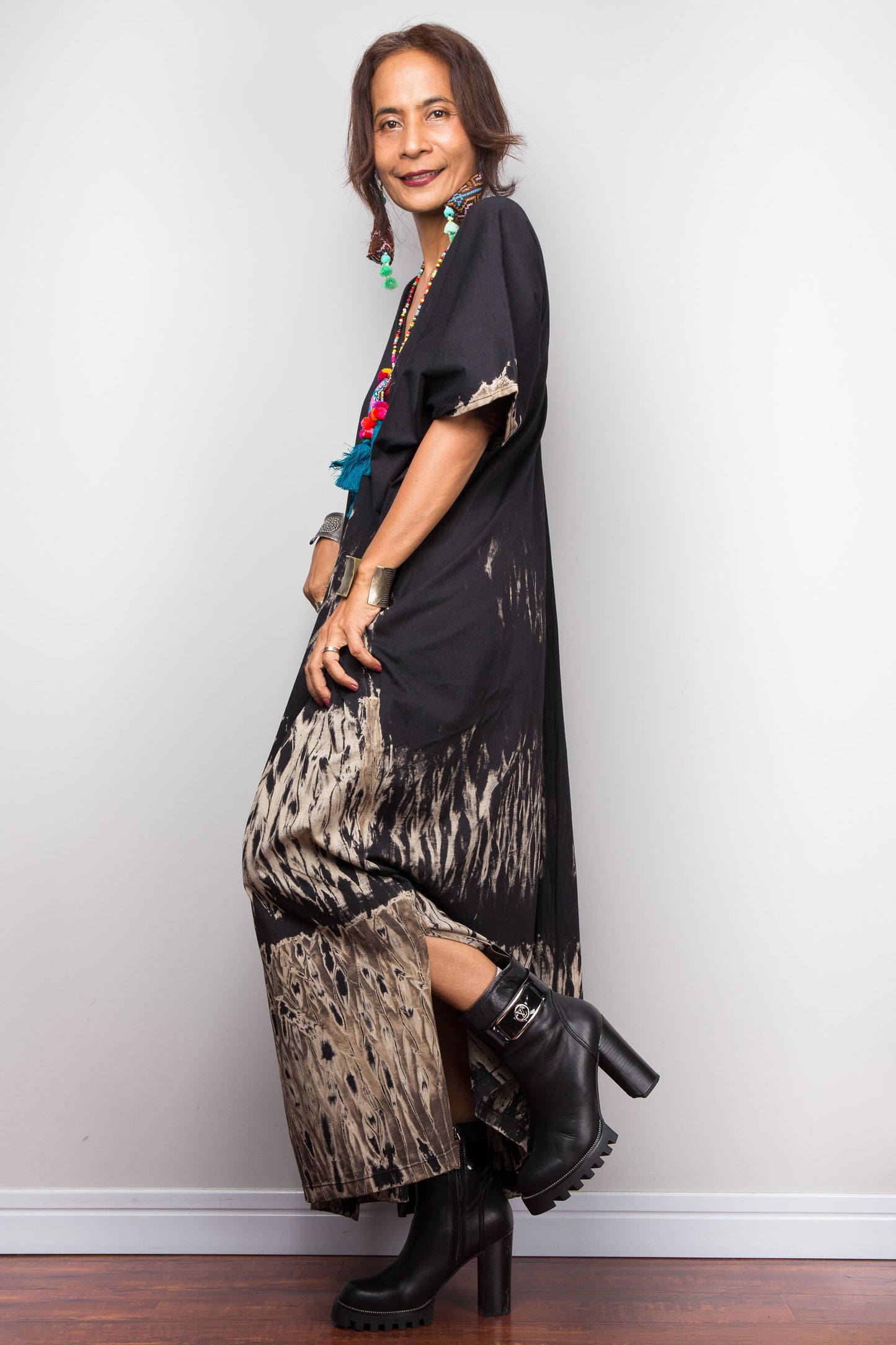 Woman wearing a black and patterned outfit with black boots against a white background