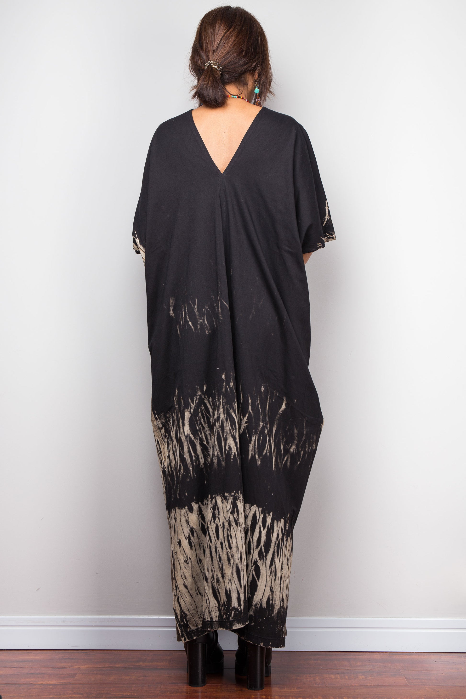 Black reverse tie dye dress with a gradient pattern worn by a person against a white wall.