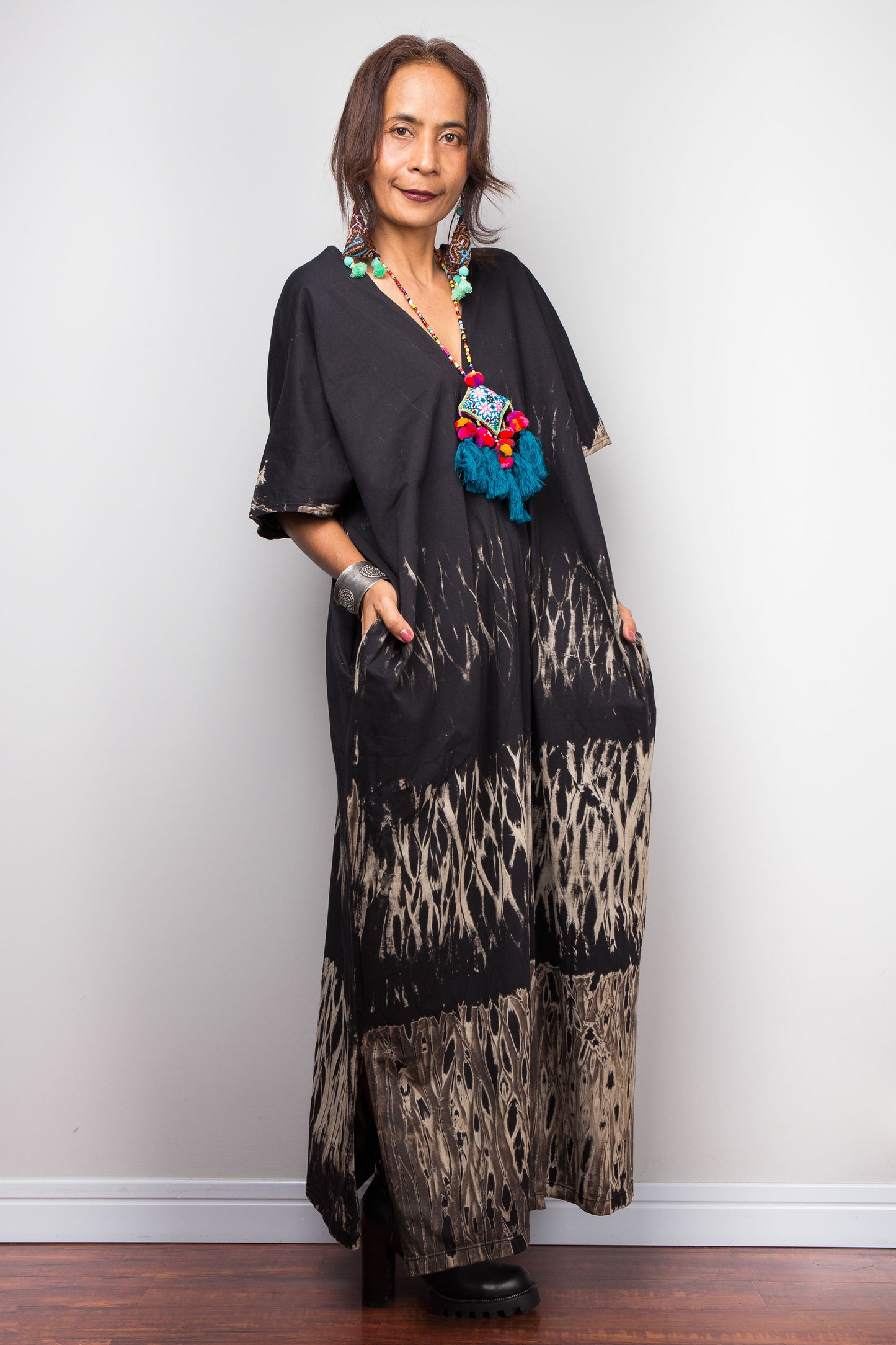 Woman wearing a black reverse tie dye dress outfit with a colorful necklace against a white background