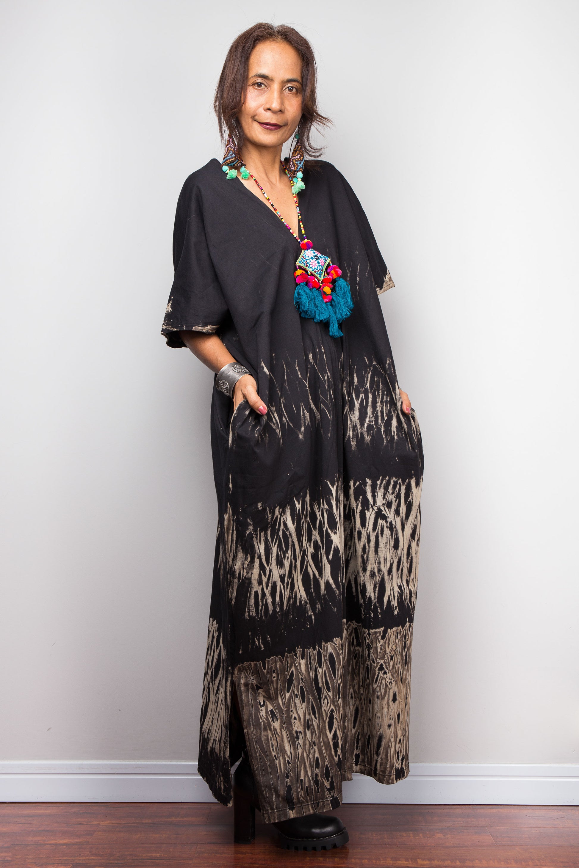 Woman wearing a black reverse tie dye dress outfit with a colorful necklace against a white background
