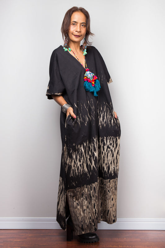 Woman wearing a black reverse tie dye dress outfit with a colorful necklace against a white background
