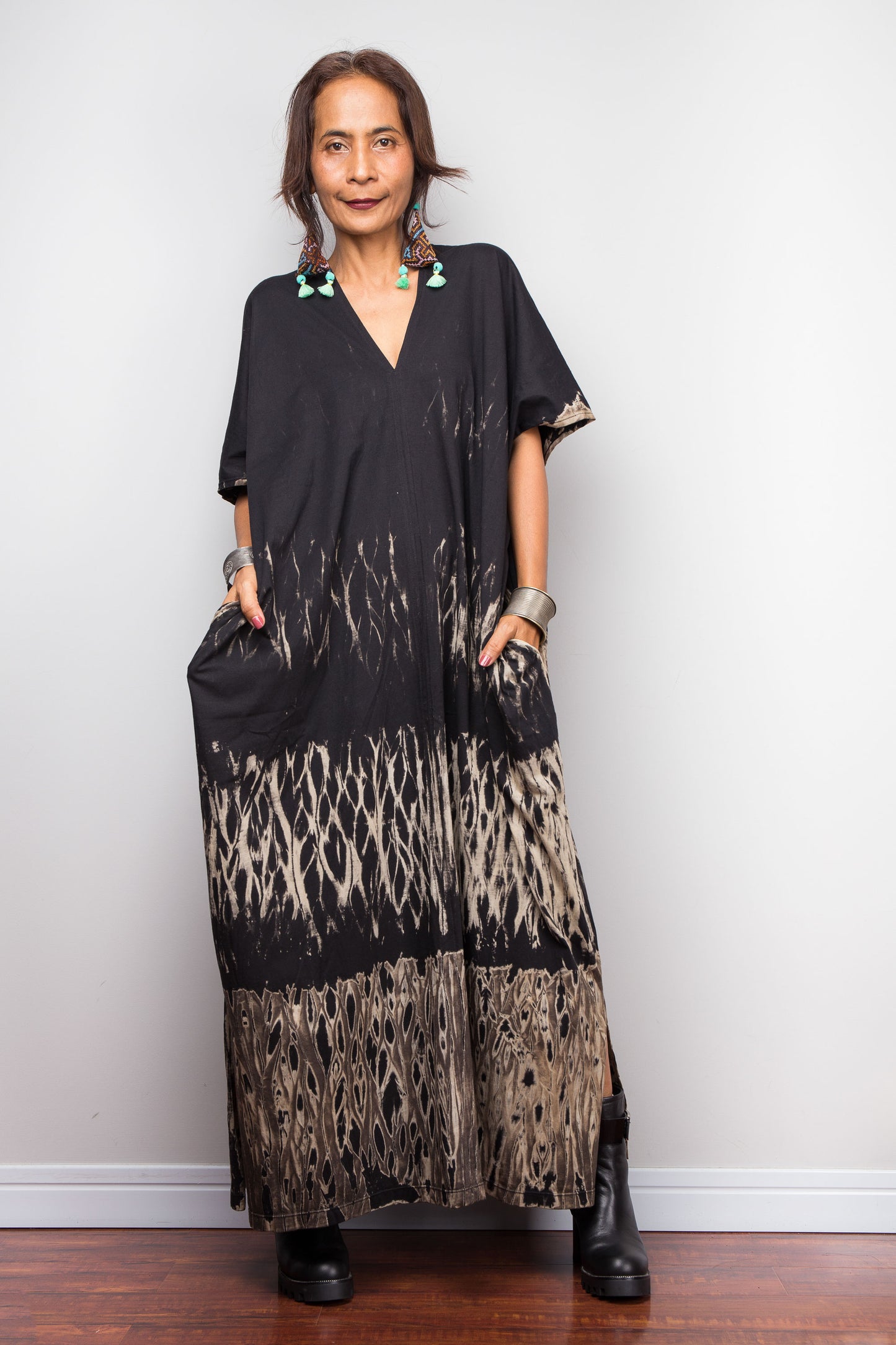 Woman wearing a cotton reverse tie dye dress against a white wall.
