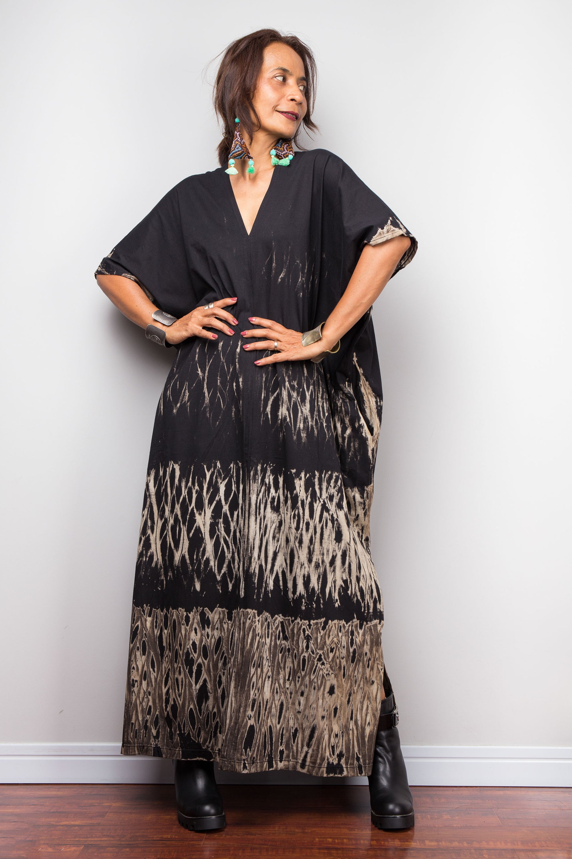 Woman wearing a black and beige reverse tie dye dress against a white wall.