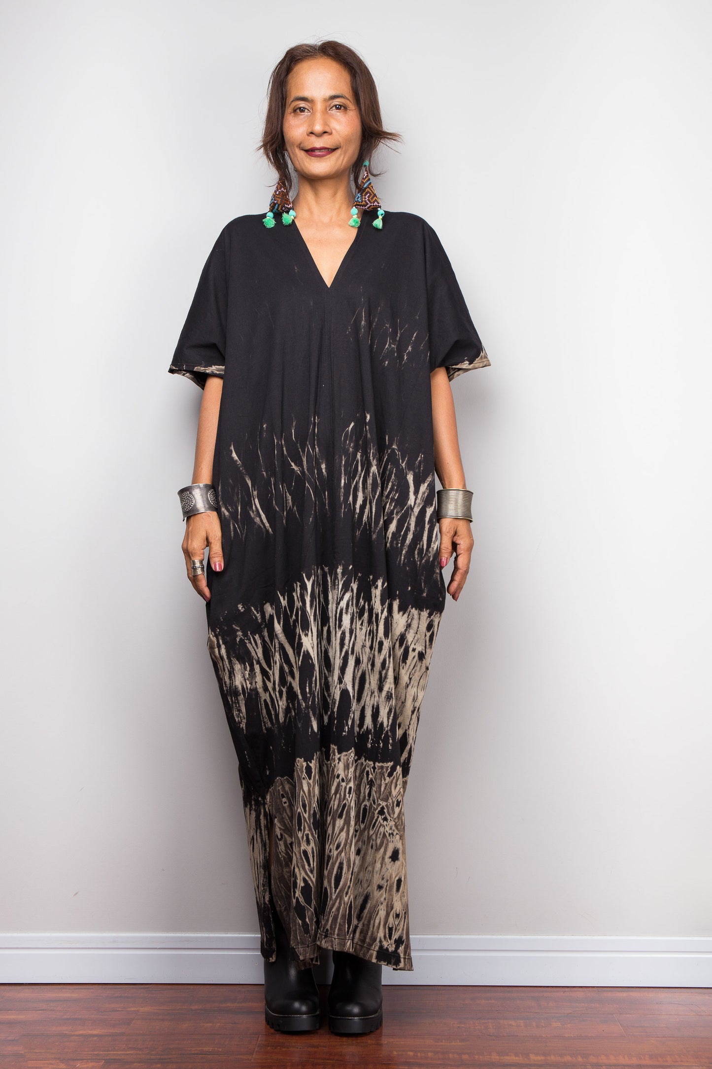 Woman wearing a unique reverse tie dye dress against a white wall.