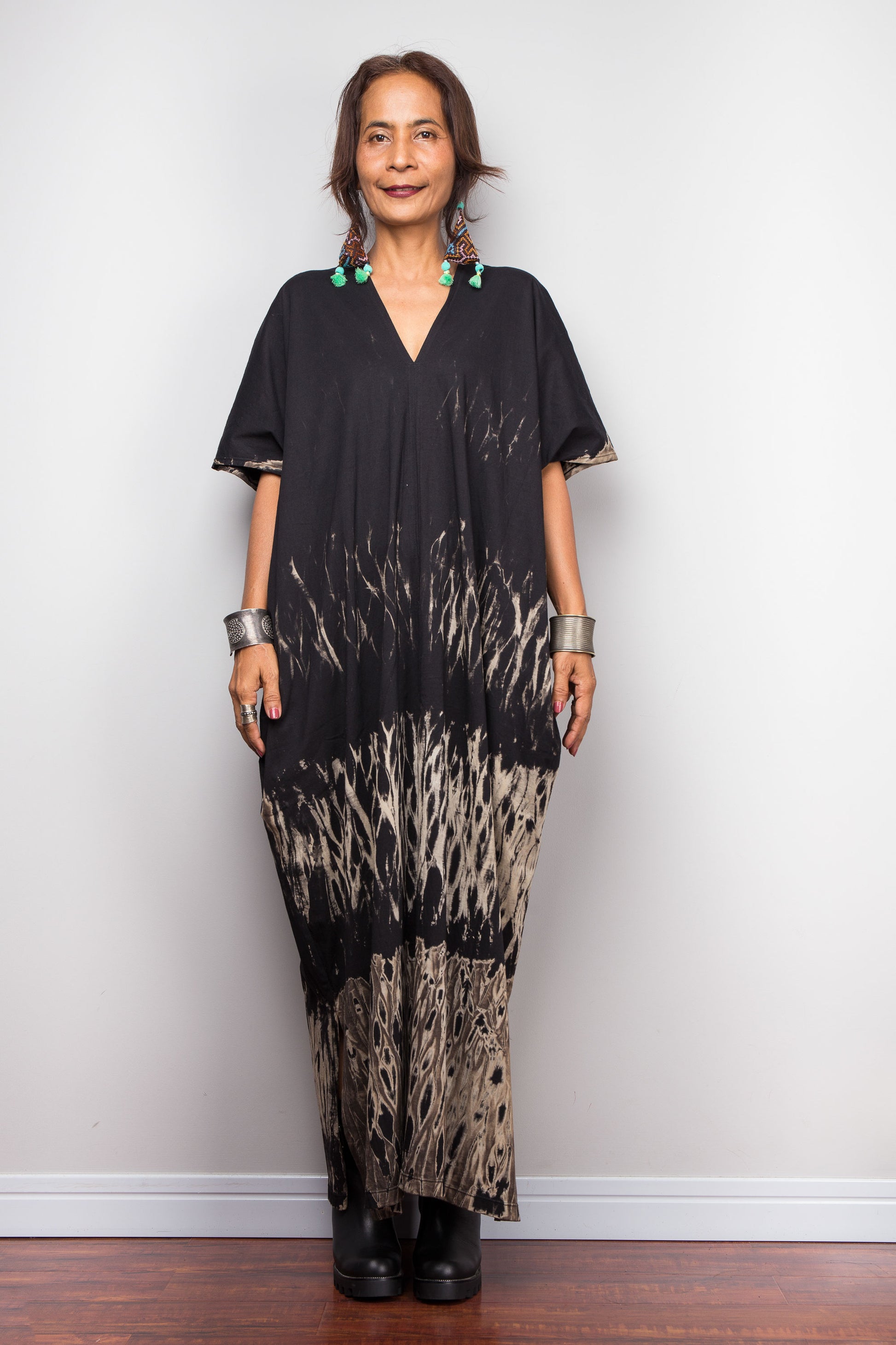 Woman wearing a unique reverse tie dye dress against a white wall.