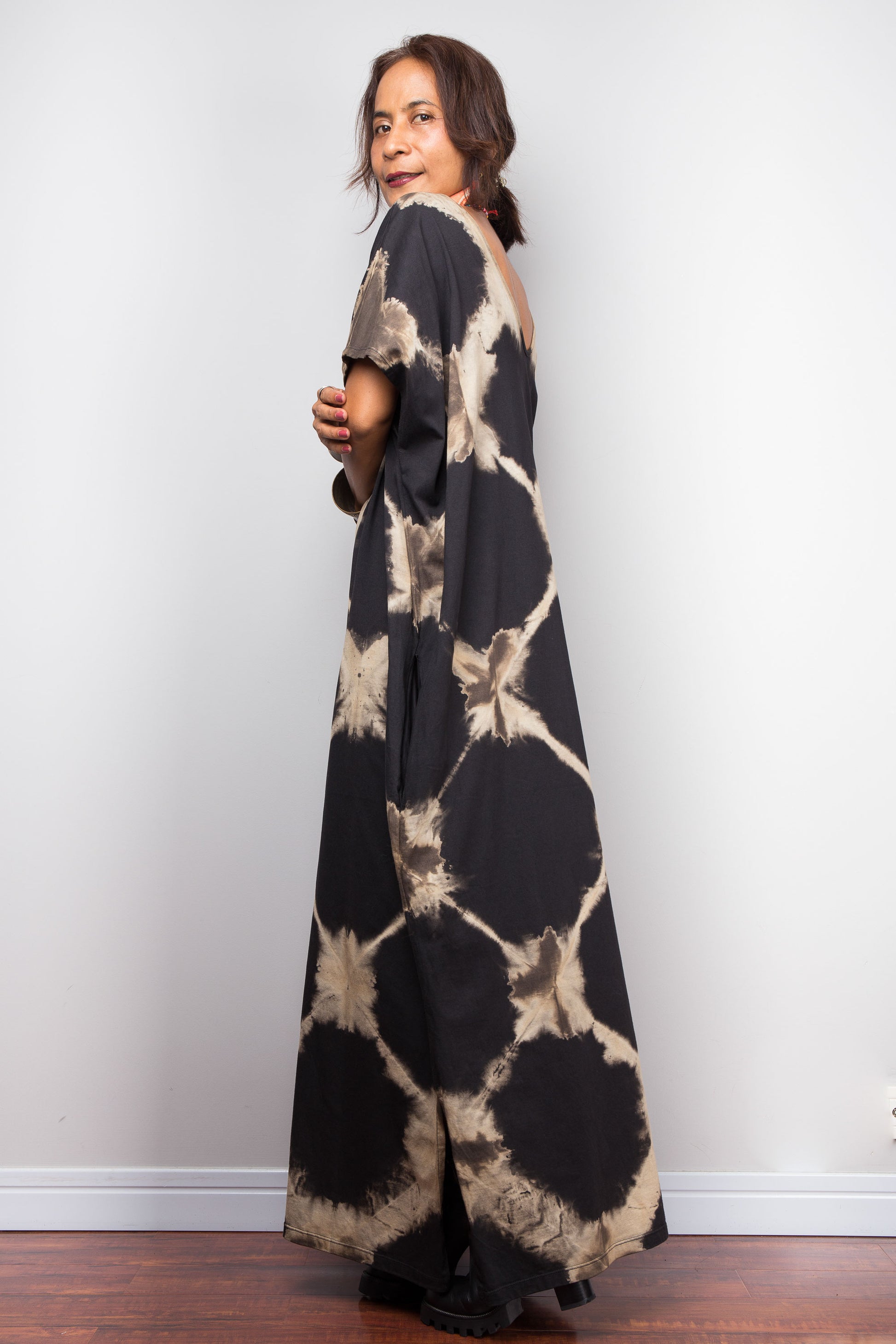 Woman wearing a tie-dye dress with a neutral pattern against a plain background