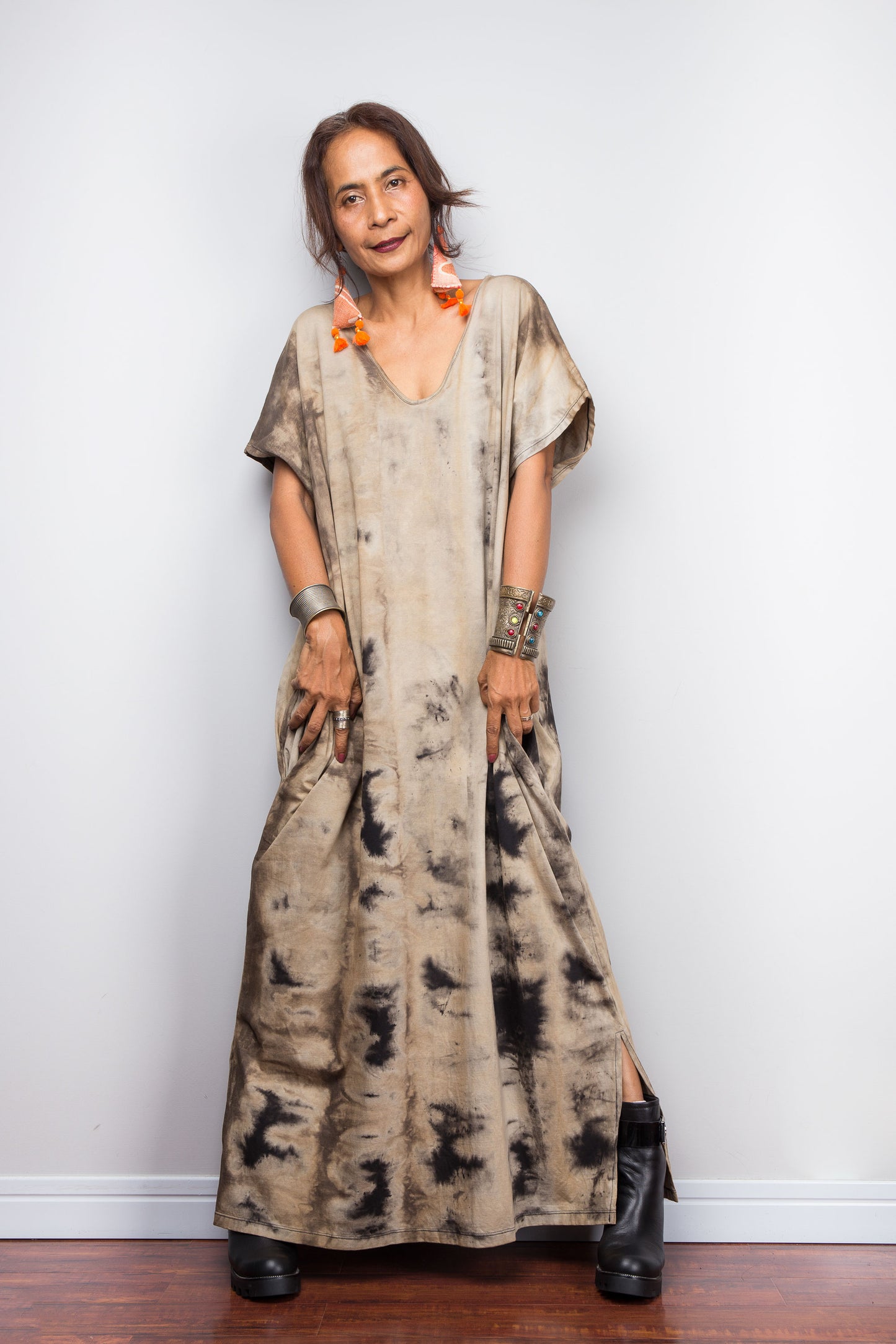 A woman showcasing a light sand-toned variant of Nuichan's oversized cotton kaftan gown, highlighting the subtle V-neck shape, short kaftan sleeves, and organic, smoke-like reverse bleach-dye patterns.