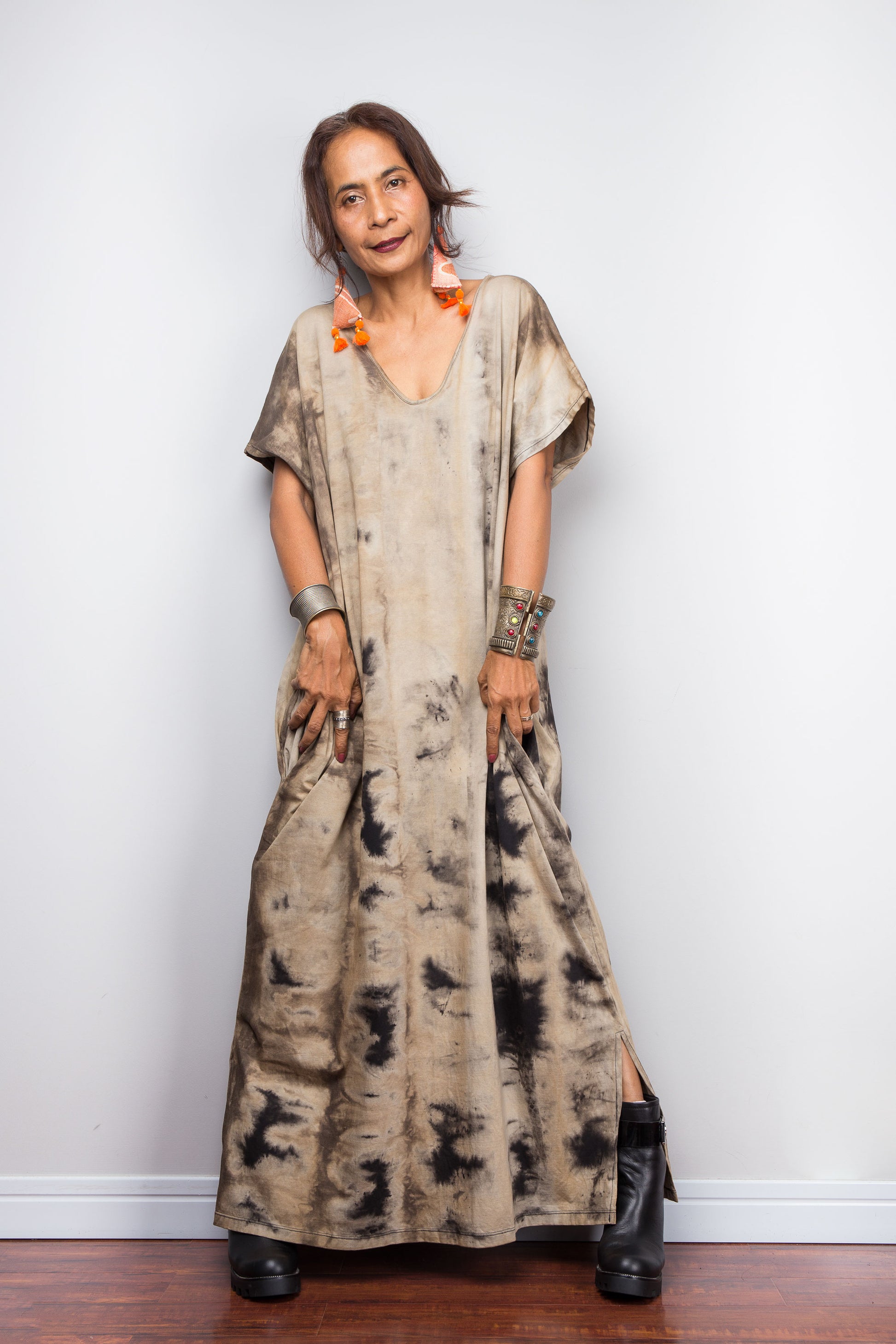 A woman showcasing a light sand-toned variant of Nuichan's oversized cotton kaftan gown, highlighting the subtle V-neck shape, short kaftan sleeves, and organic, smoke-like reverse bleach-dye patterns.
