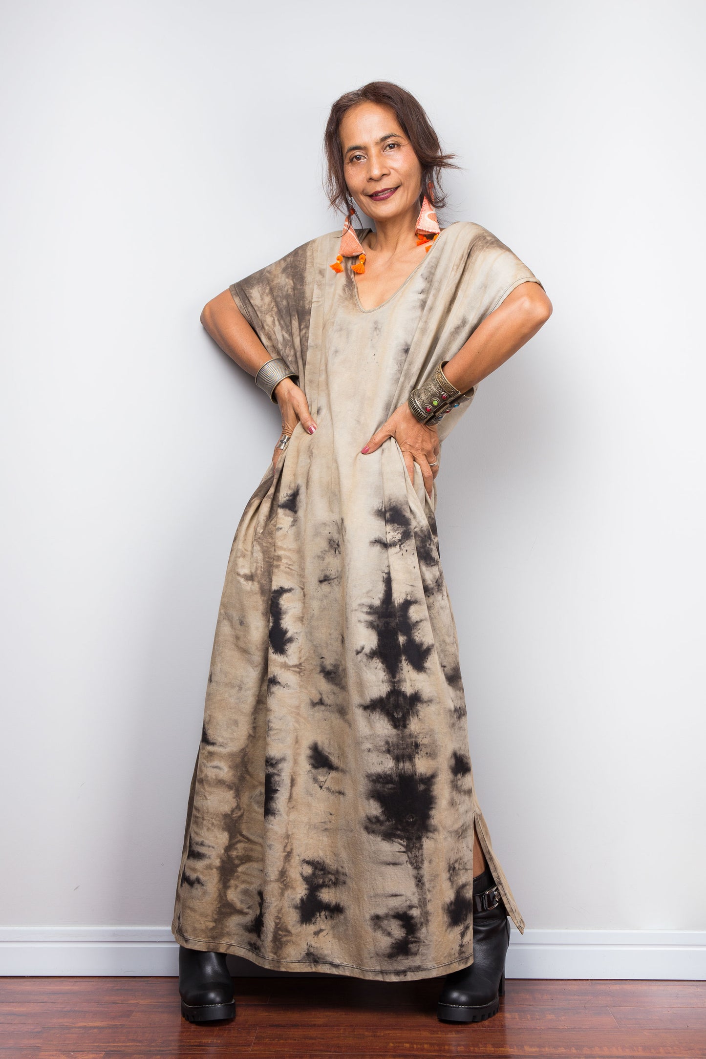 Full front view of a model in an authentic Nuichan brand reverse tie-dye kaftan maxi dress, featuring a soft sand and beige canvas with dark abstract watercolor bleeding patterns and a V-neckline and side split at the hem