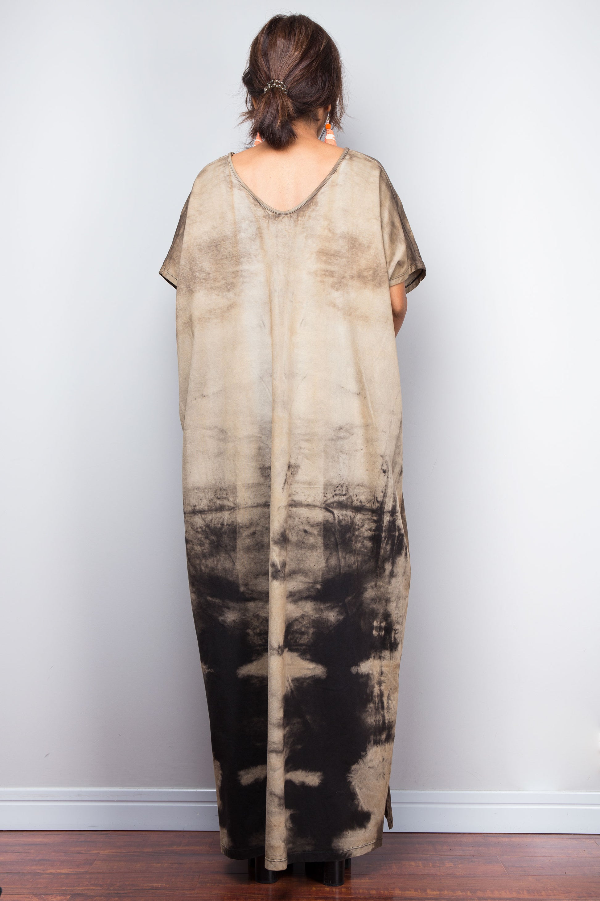 Back view of a model styling Nuichan's oversized reverse tie-dye kaftan dress, showcasing the loose fit and sand-colored pattern.