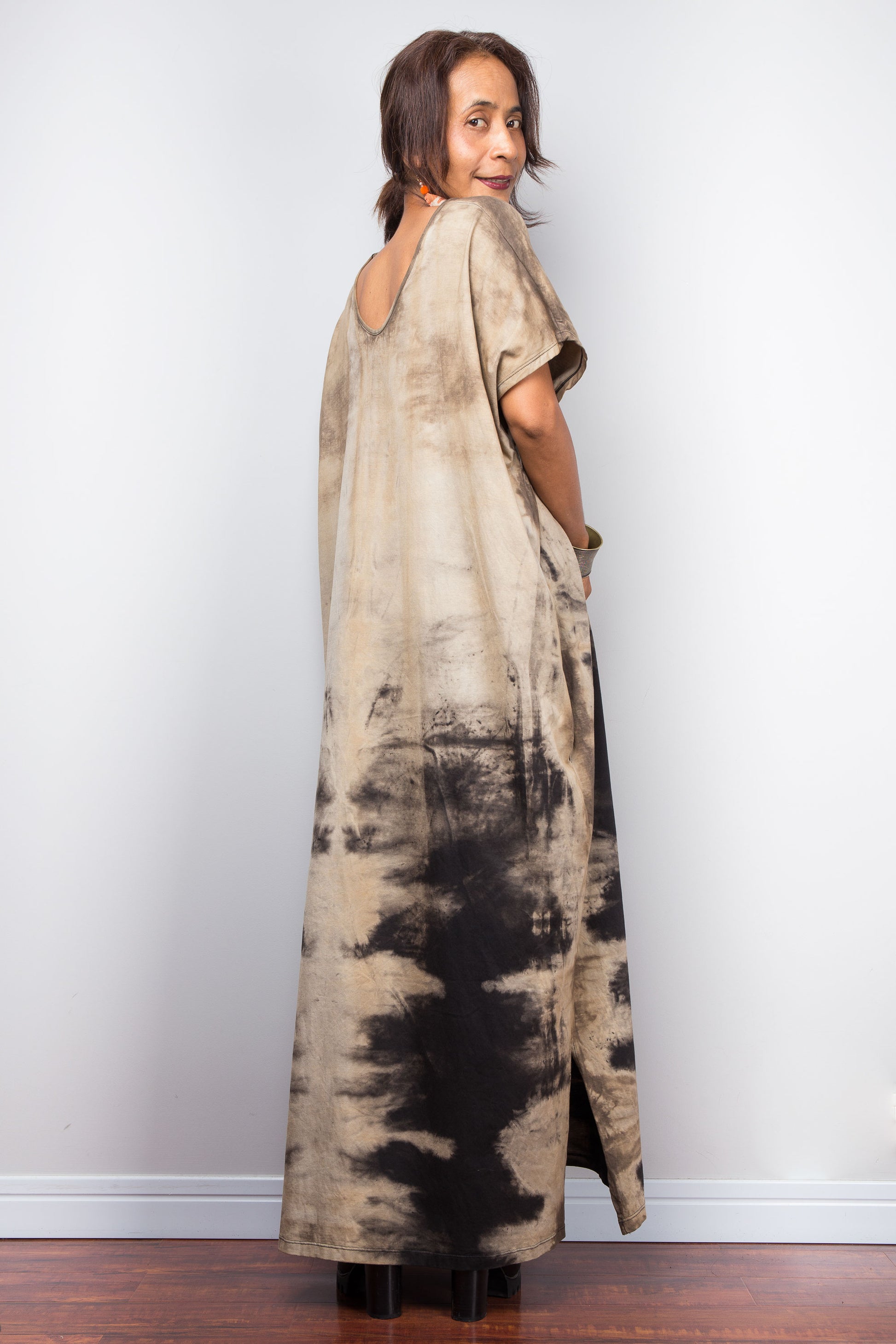 Back view of a model styling Nuichan's oversized reverse tie-dye kaftan dress, showcasing the loose fit, split at hem and sand-colored pattern.