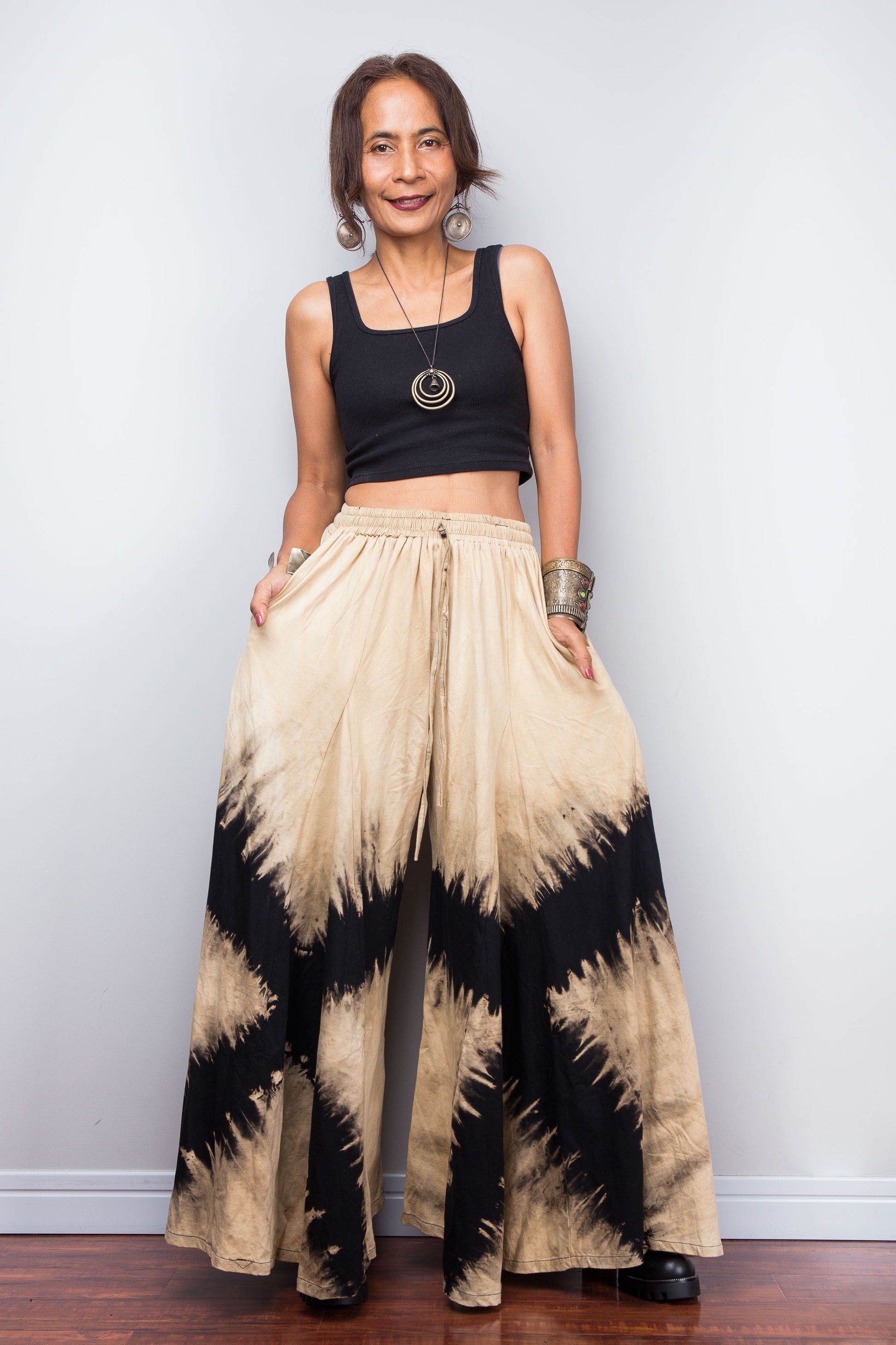 Authentic Nuichan brand reverse tie dye wide leg palazzo pants in black and sand cotton, featuring a prominent high-contrast abstract diamond starburst pattern, styled high-waisted on a model