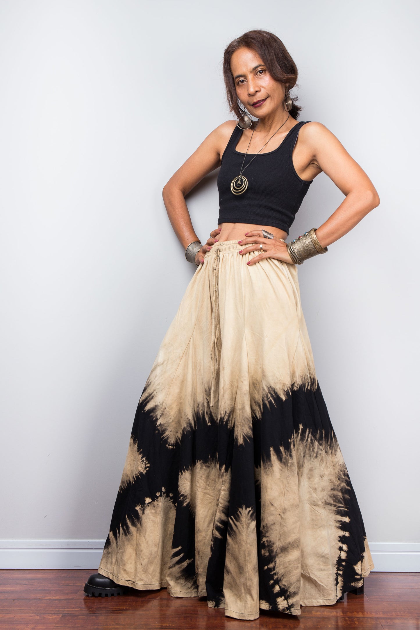Petite Model posing dynamically to showcase the immense fabric volume of Nuichan's oversized reverse tie dye palazzo pants, illustrating the skirt-like flow and dramatic movement of the unstructured wide legs.