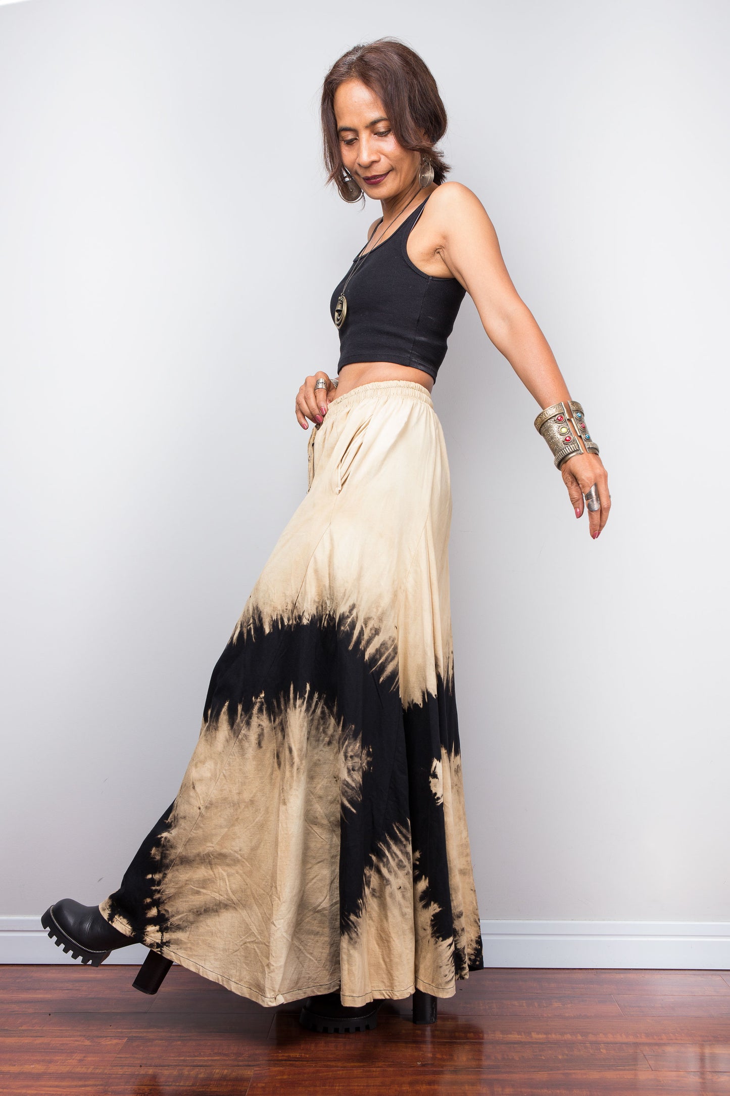 Petite Woman wearing an original Nuichan brand, black and beige reverse tie dye pair of pants against a plain background