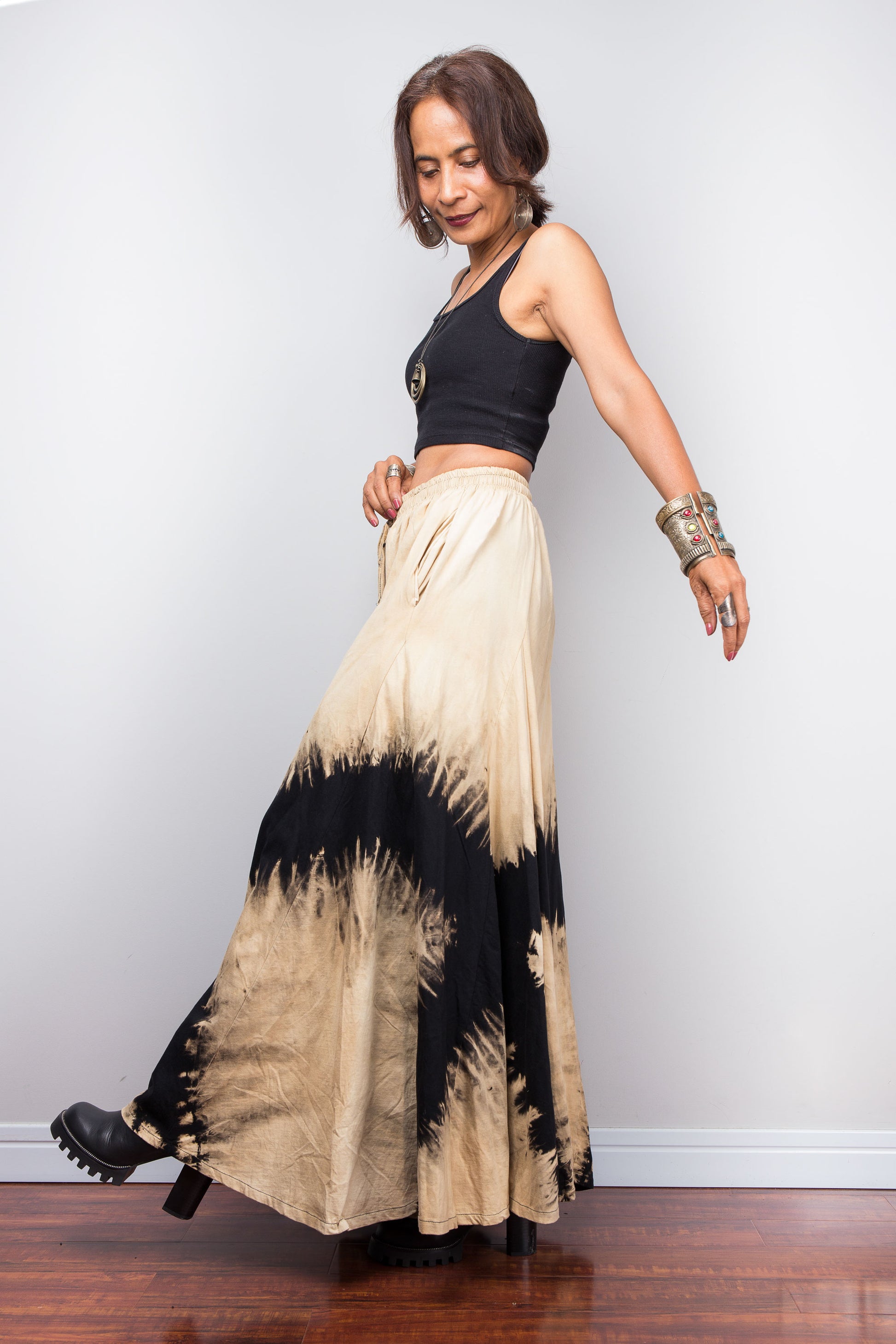 Petite Woman wearing an original Nuichan brand, black and beige reverse tie dye pair of pants against a plain background