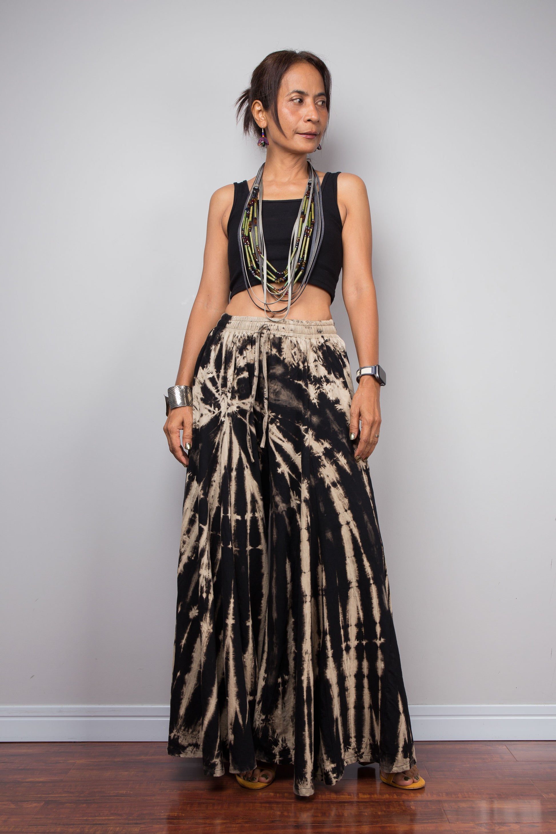 Woman wearing black and beige tie-dye pants against a plain background