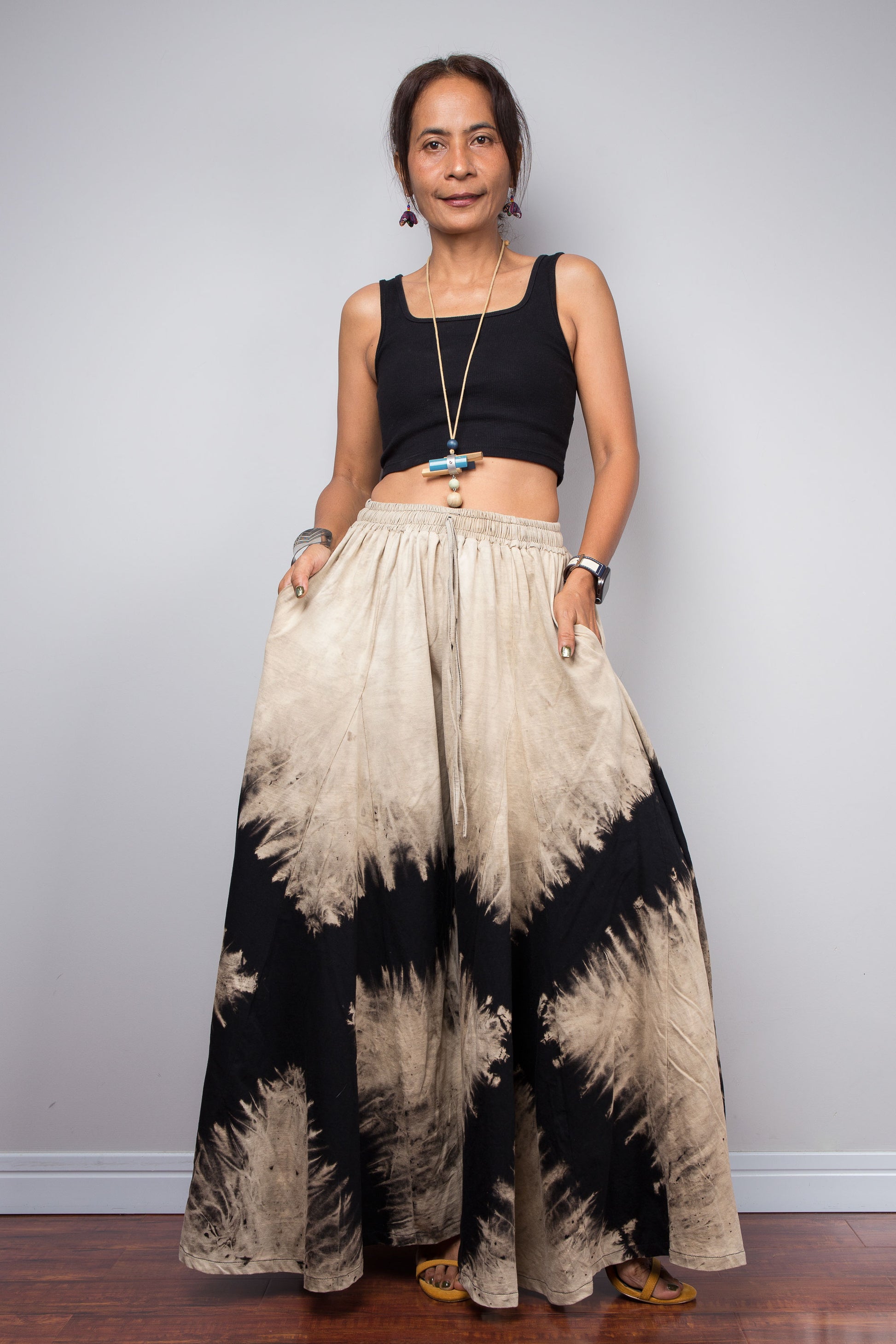 Authentic Nuichan brand reverse tie dye wide leg palazzo pants in black and sand cotton, featuring a prominent high-contrast abstract diamond starburst pattern, styled high-waisted on a model