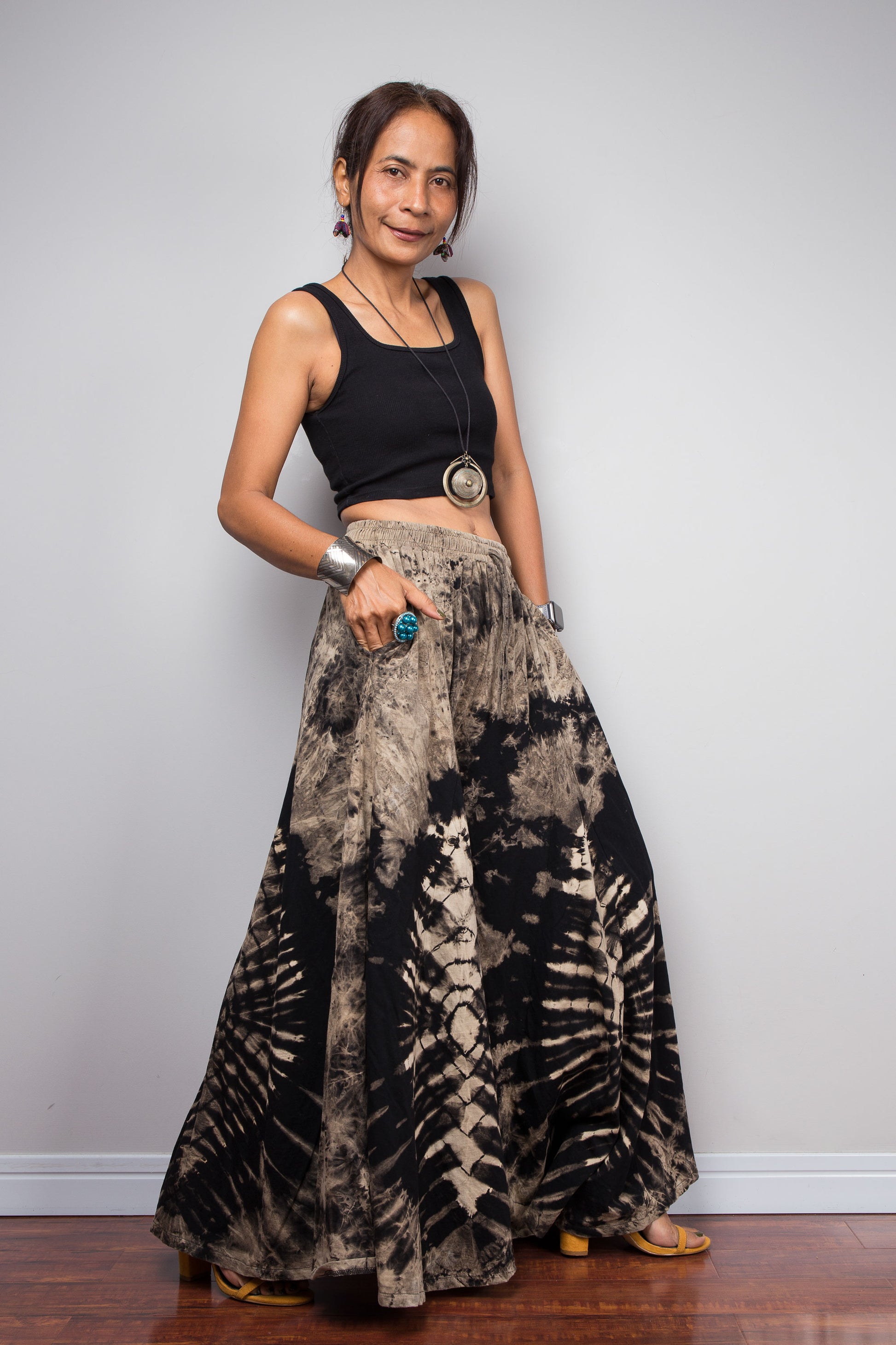 Side view of a model wearing the Nuichan reverse tie dye palazzo pants, showcasing the functional hidden side pocket and the fluid cotton drape of the ultra-wide leg silhouette in black and sand tones