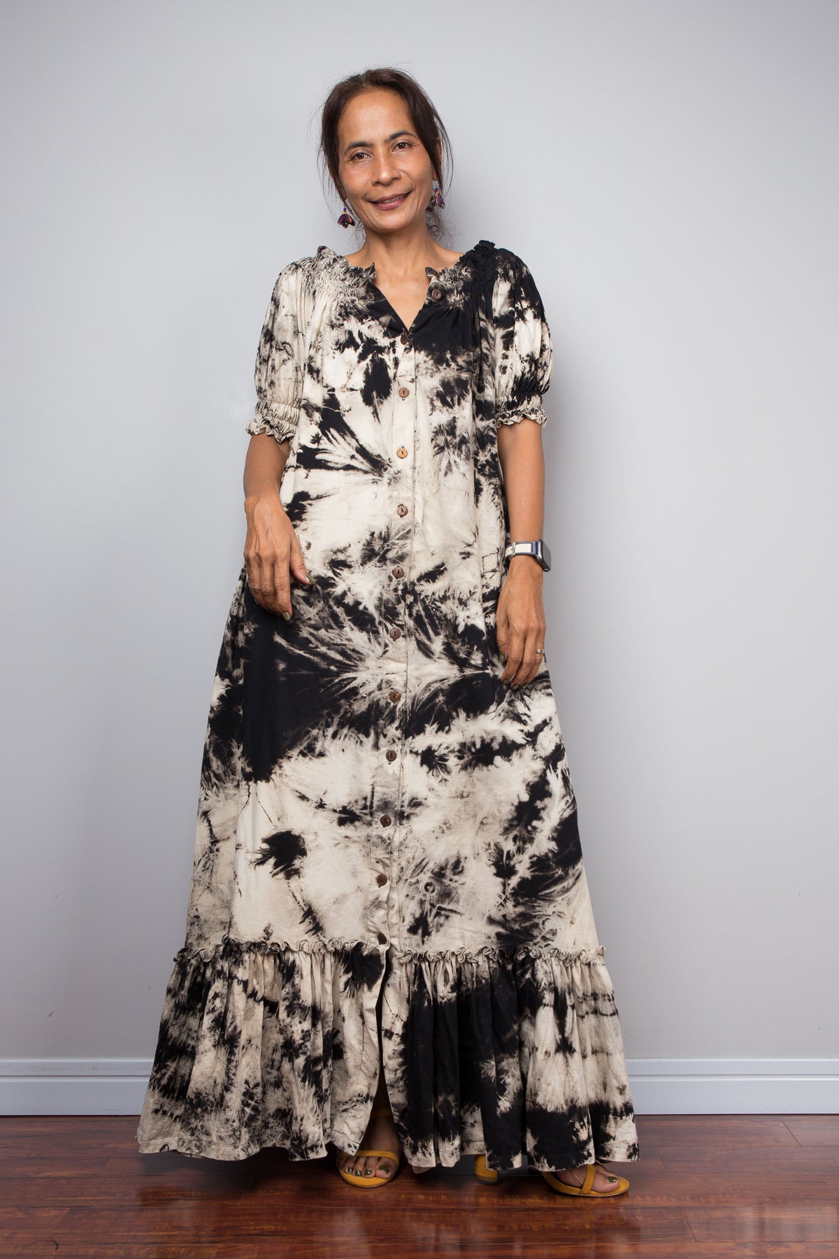 Front view of a model wearing the Nuichan reverse tie dye maxi shirt dress with buttons partially undone at collar and at the hem, demonstrating the adjustable walking slit detail and the sweeping tiered ruffle hem in motion