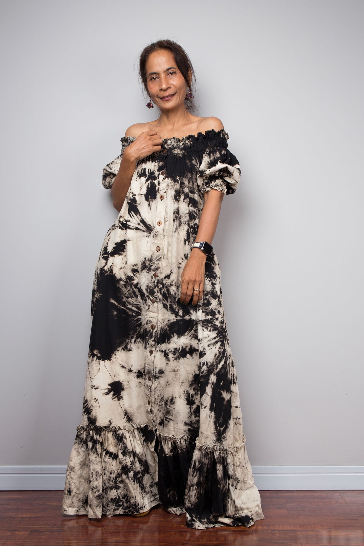Woman wearing a black and white tie-dye dress against a plain background