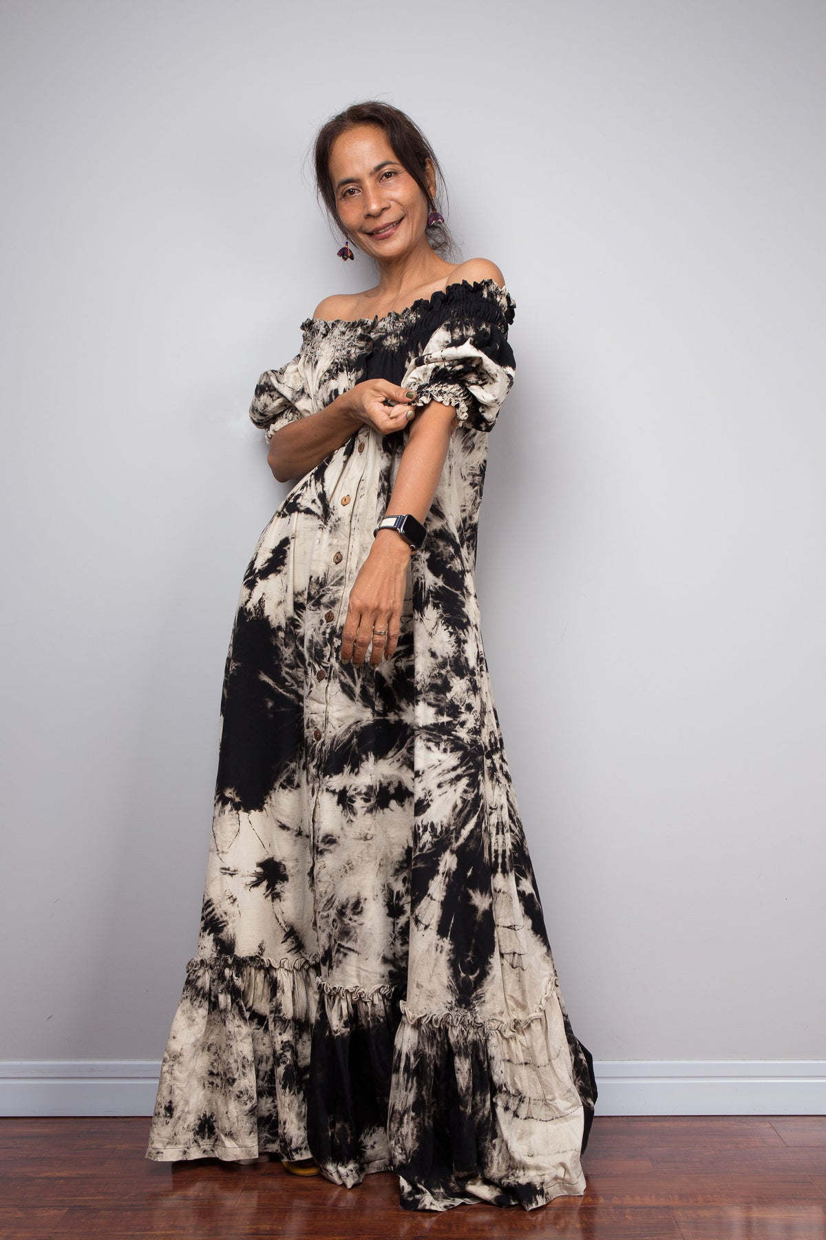 Full-length front view of a model in the Nuichan reverse tie dye off-shoulder button-down maxi dress, showcasing the complete silhouette from elasticated smocked neckline to tiered ruffle hem with deep side pockets