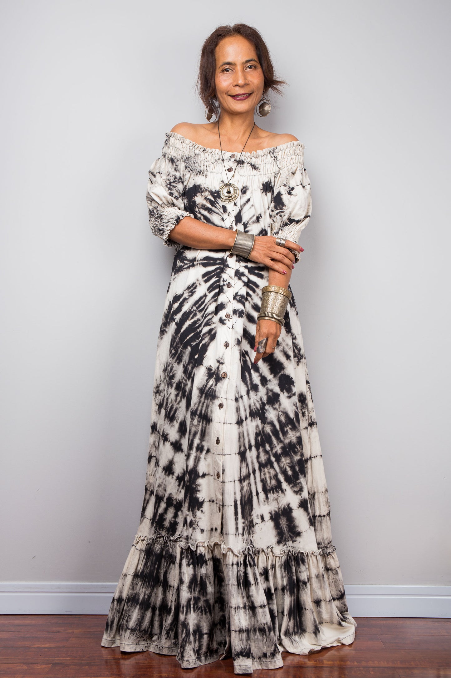 Front view of a model styling the Nuichan reverse tie-dye maxi dress off-the-shoulder, showcasing the smocked top part of the bodice and dramatic monochrome spiral pattern.