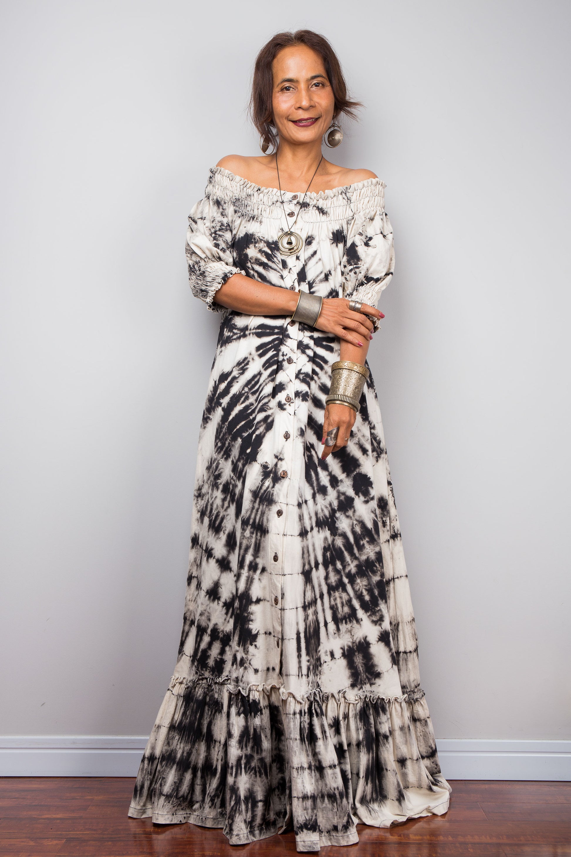 Front view of a model styling the Nuichan reverse tie-dye maxi dress off-the-shoulder, showcasing the smocked top part of the bodice and dramatic monochrome spiral pattern.