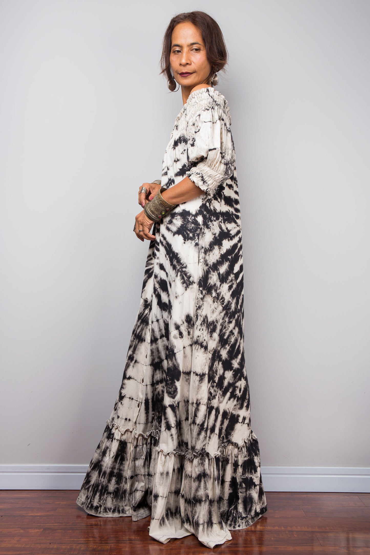 Side view of a model styling the Nuichan reverse tie-dye maxi dress off-the-shoulder, showcasing the monochrome spiral pattern.
