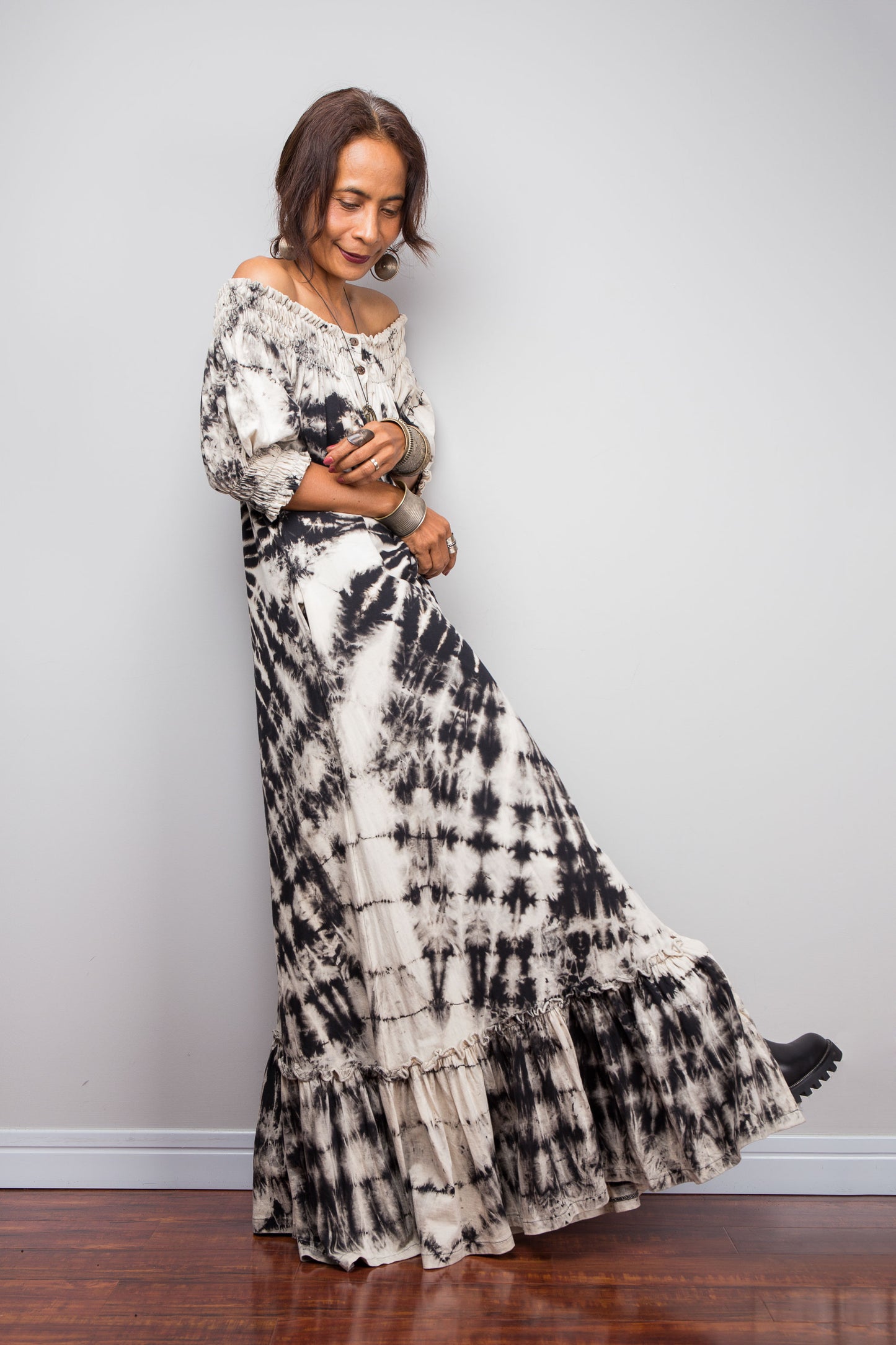 Front view of a model styling the Nuichan reverse tie-dye maxi dress off-the-shoulder, showcasing the black and sand spiral pattern.
