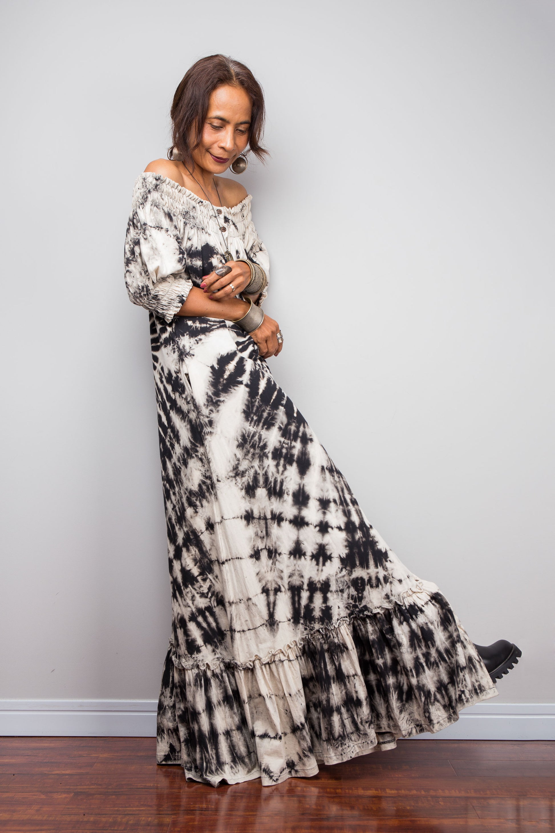 Front view of a model styling the Nuichan reverse tie-dye maxi dress off-the-shoulder, showcasing the black and sand spiral pattern.