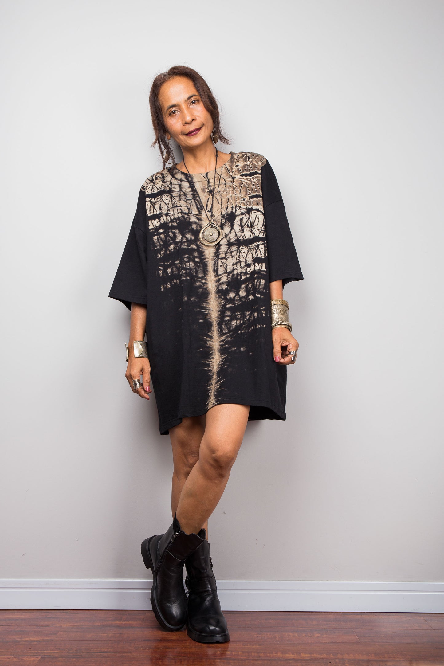Front view of a model styling Nuichan's oversized reverse tie-dye t-shirt dress with black boots, showcasing the loose boxy fit and vertical sand-colored starburst pattern