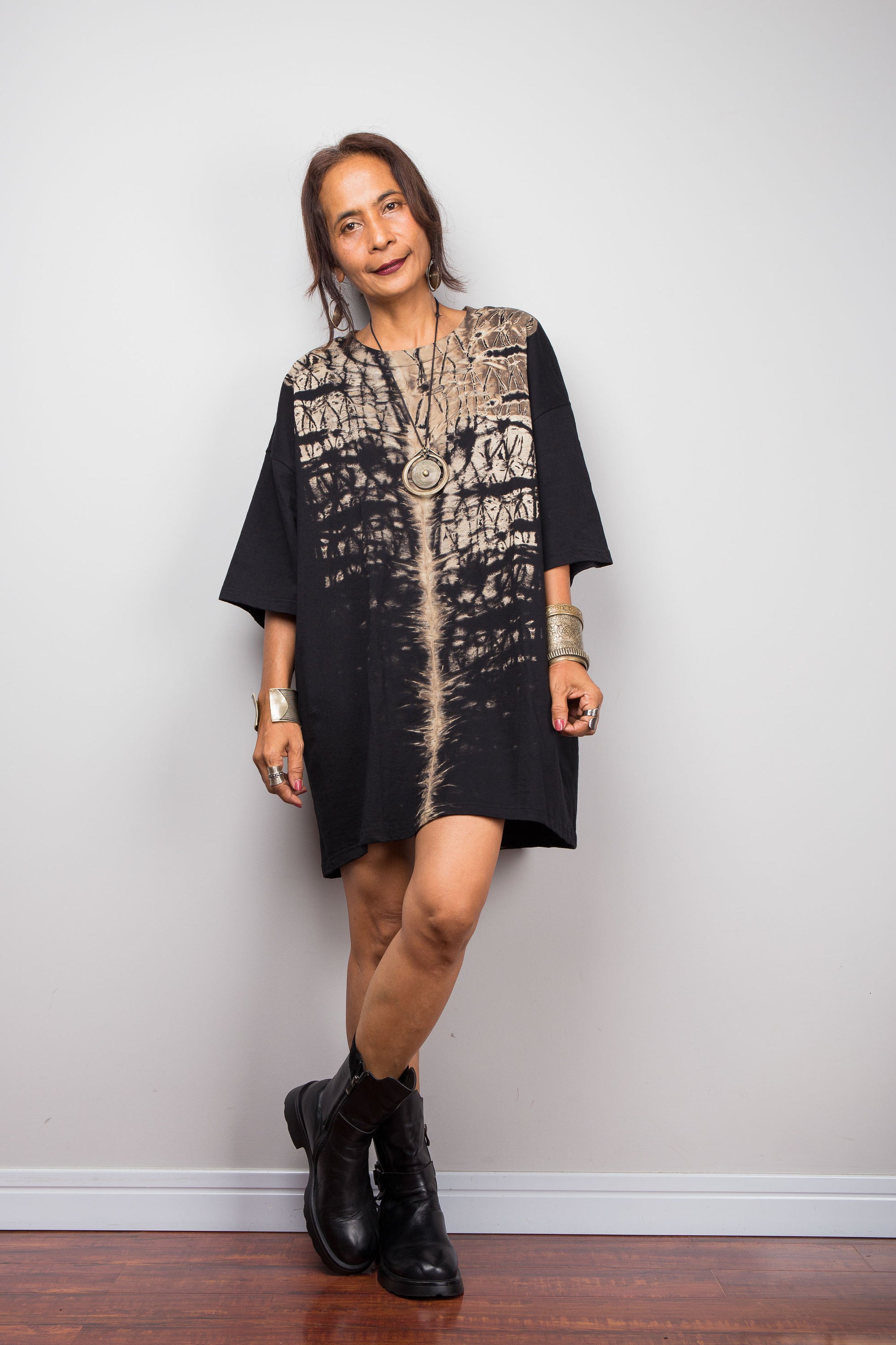 Front view of a model styling Nuichan's oversized reverse tie-dye t-shirt dress with black boots, showcasing the loose boxy fit and vertical sand-colored starburst pattern