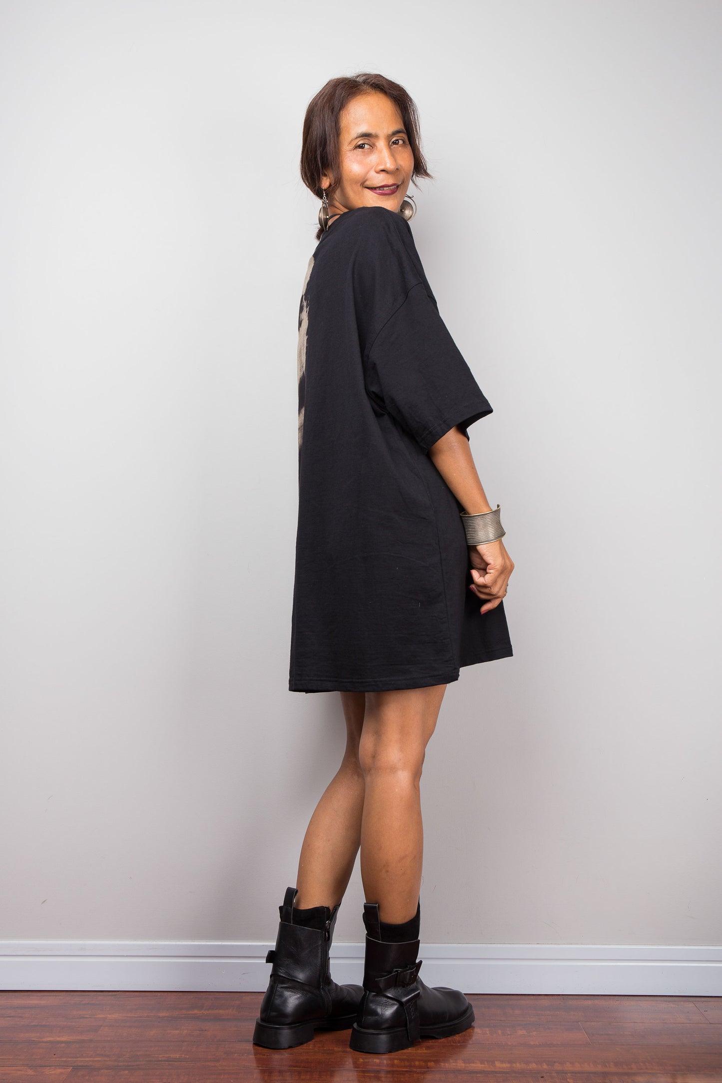 Side view of a petite woman styling Nuichan's oversized reverse tie-dye tee with black boots, showcasing the loose boxy fit and sand-colored pattern