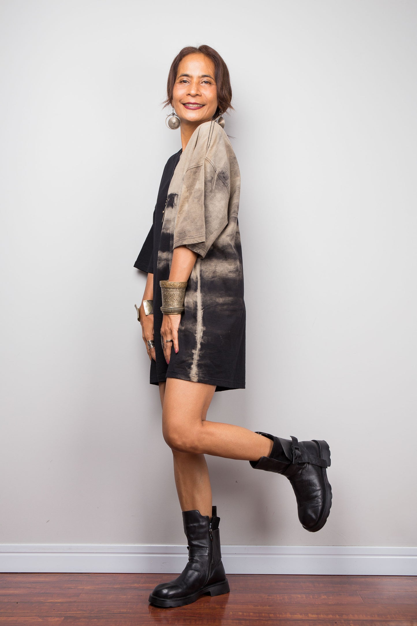 Side view of a female model styling Nuichan's oversized reverse tie-dye tee with black boots, showcasing the loose boxy fit and sand-colored pattern