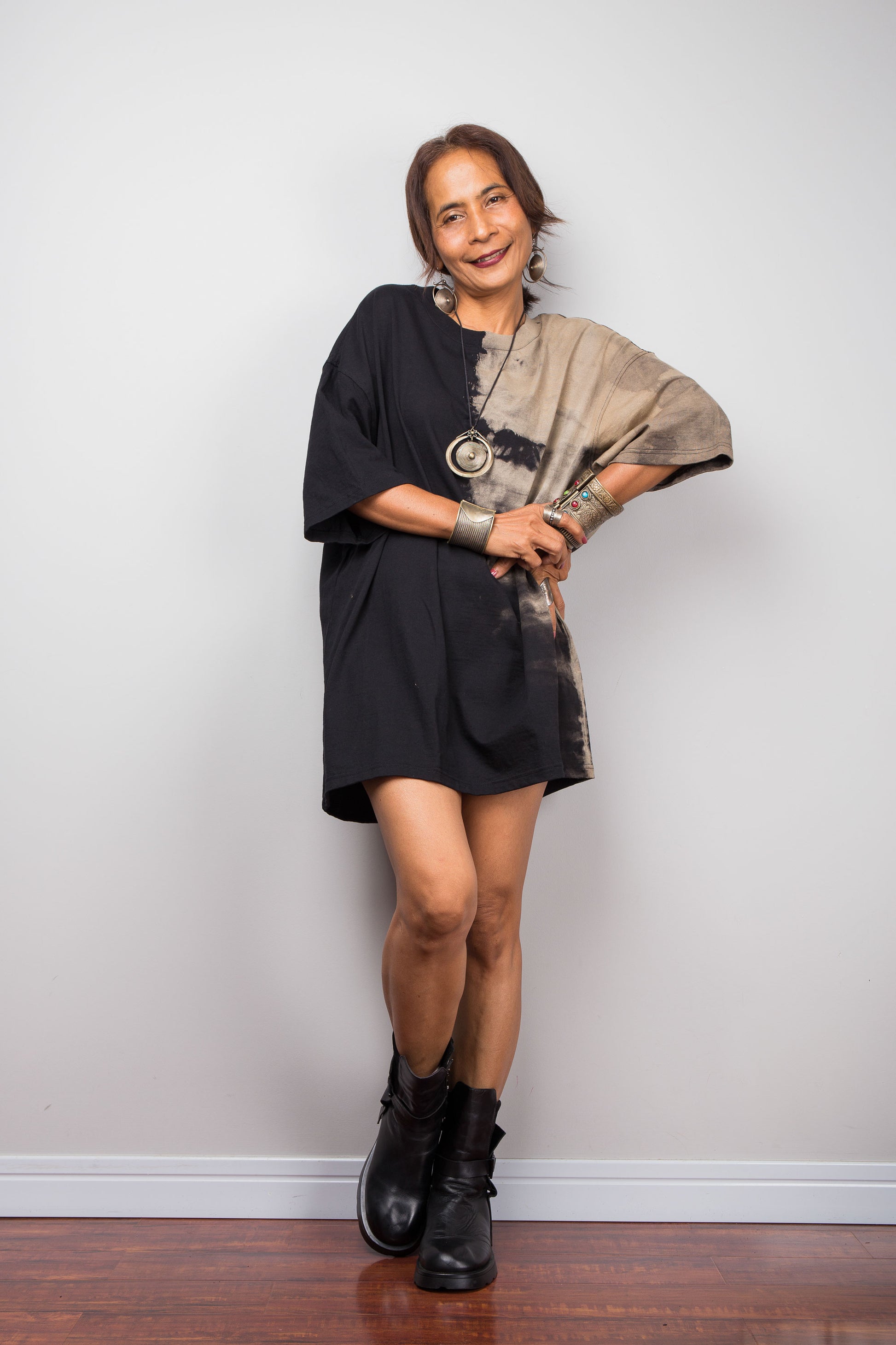 Woman wearing a black dress with a patterned tie dye against a plain background