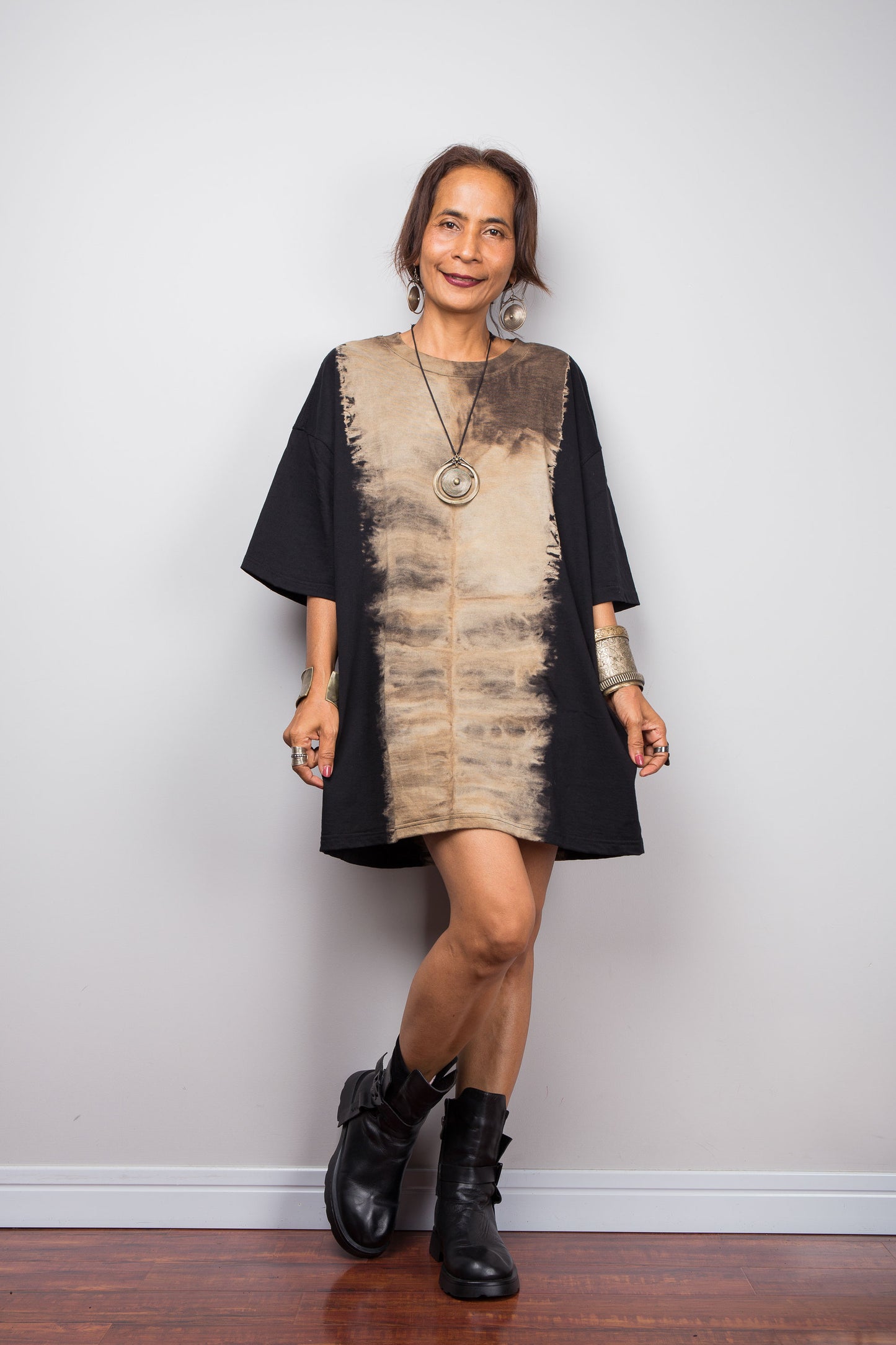 Front view of a model styling Nuichan's oversized reverse tie dye t-shirt with black boots, showcasing the loose boxy fit and vertical sand-colored starburst pattern.