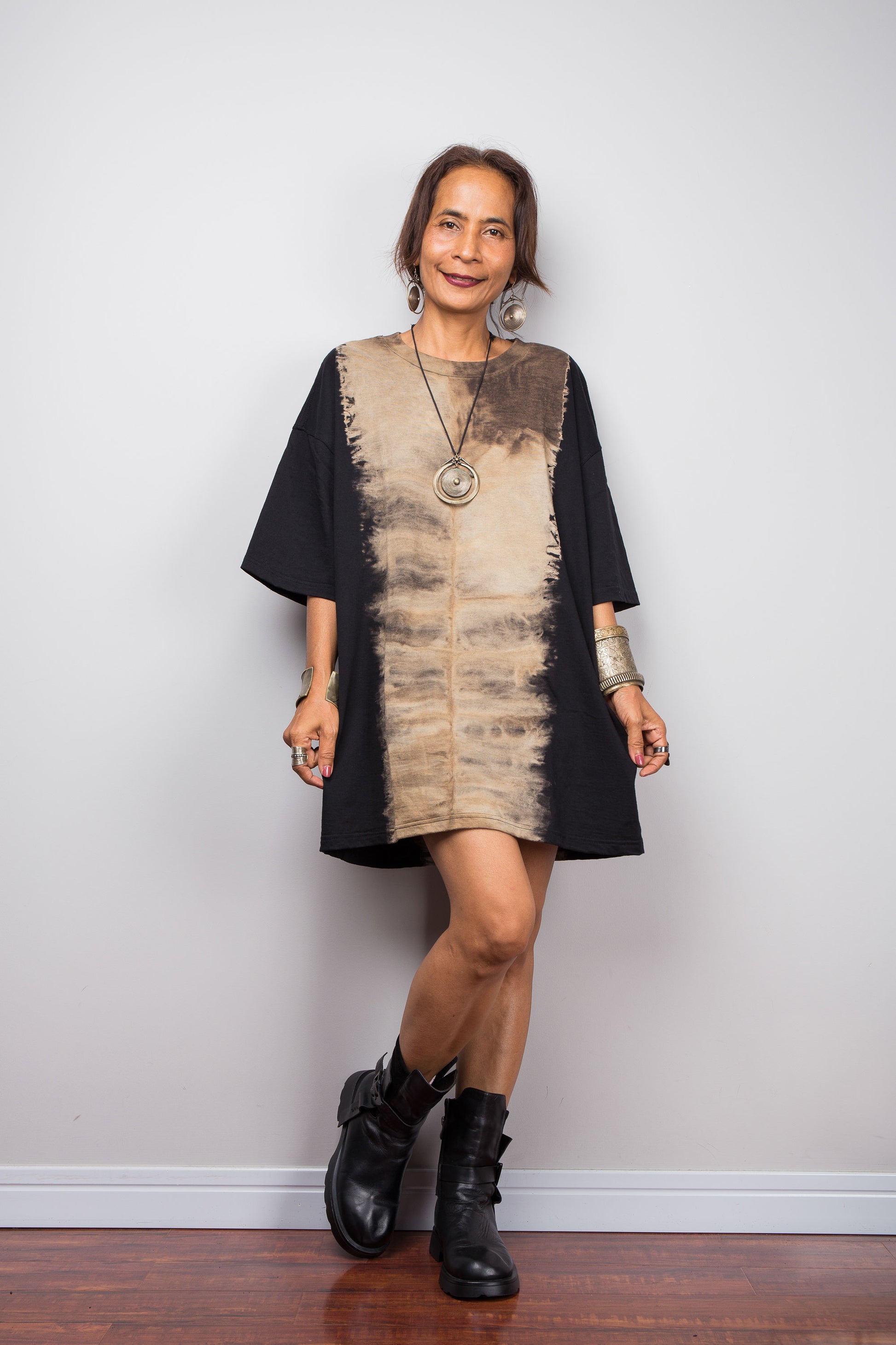 Front view of a model styling Nuichan's oversized reverse tie dye t-shirt with black boots, showcasing the loose boxy fit and vertical sand-colored starburst pattern.