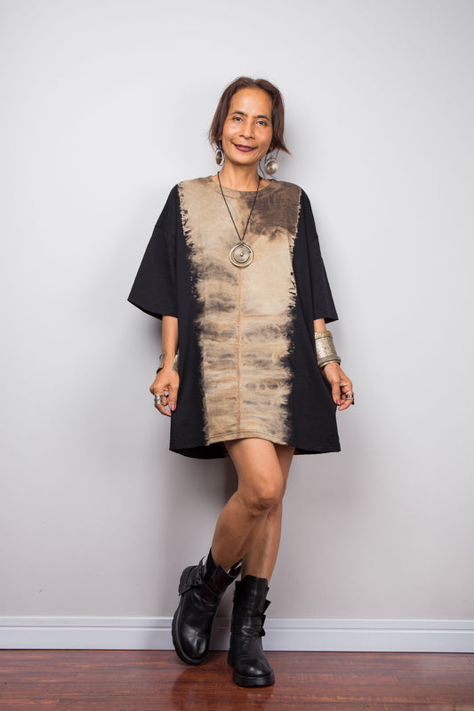 Front view of a model styling Nuichan's oversized reverse tie dye t-shirt with black boots, showcasing the loose boxy fit and vertical sand-colored starburst pattern.