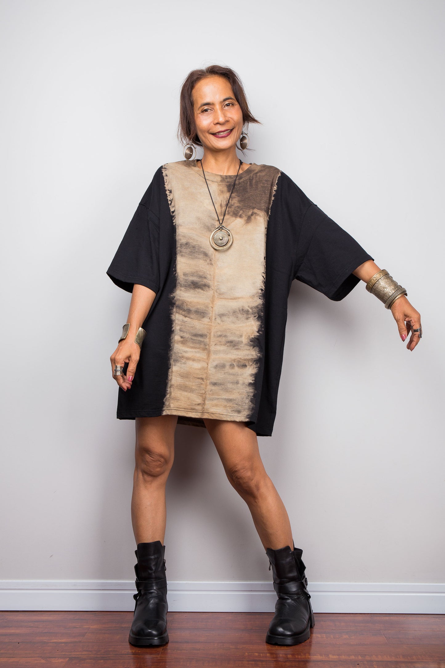Front view of a model styling Nuichan's oversized bleached tie dye t-shirt with black boots, showcasing the loose boxy fit and vertical sand-colored starburst pattern.