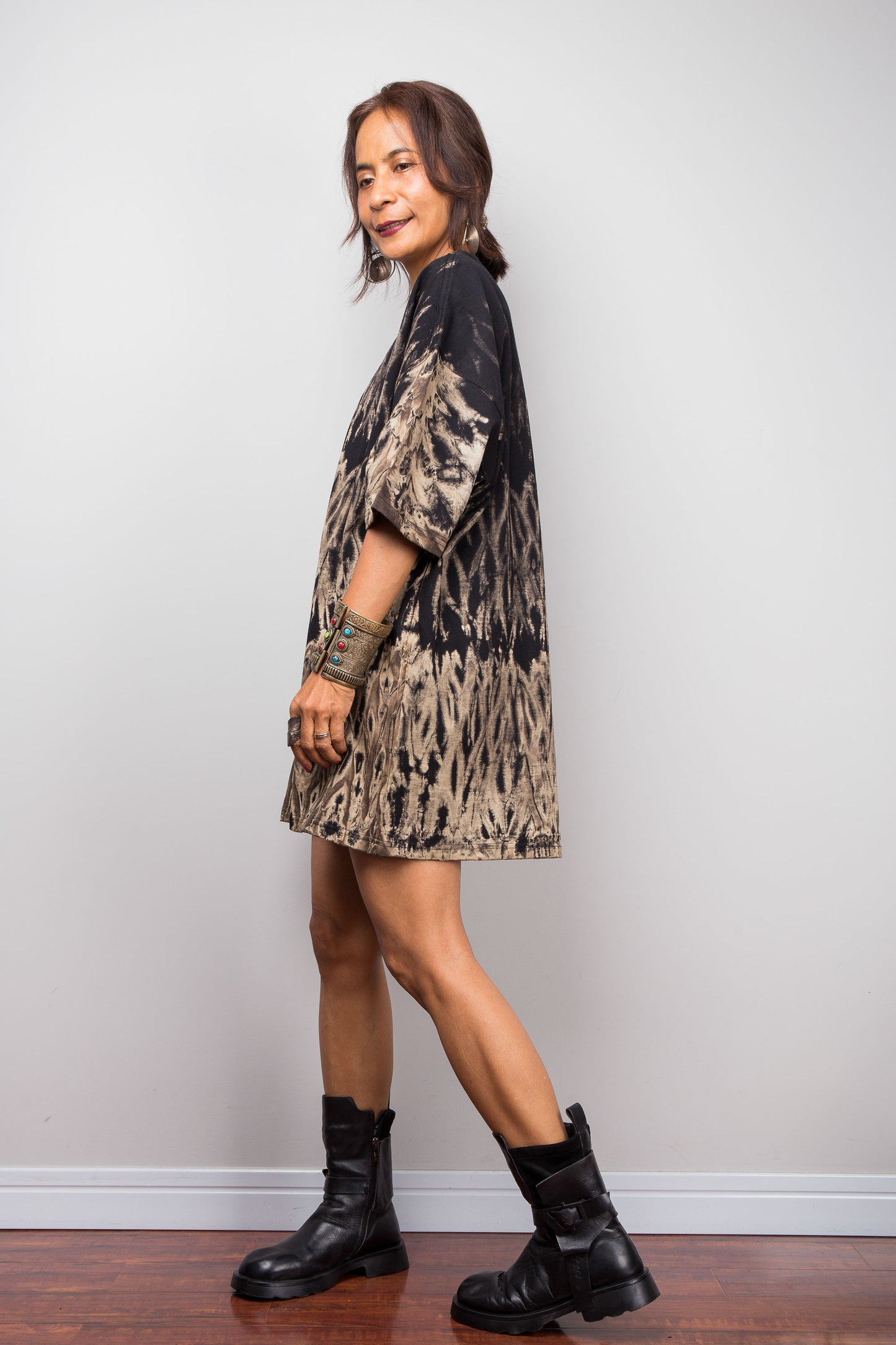 Side view of a petite woman styling Nuichan's oversized reverse tie-dye t-shirt, showcasing the loose boxy fit and black with sand-colored pattern.