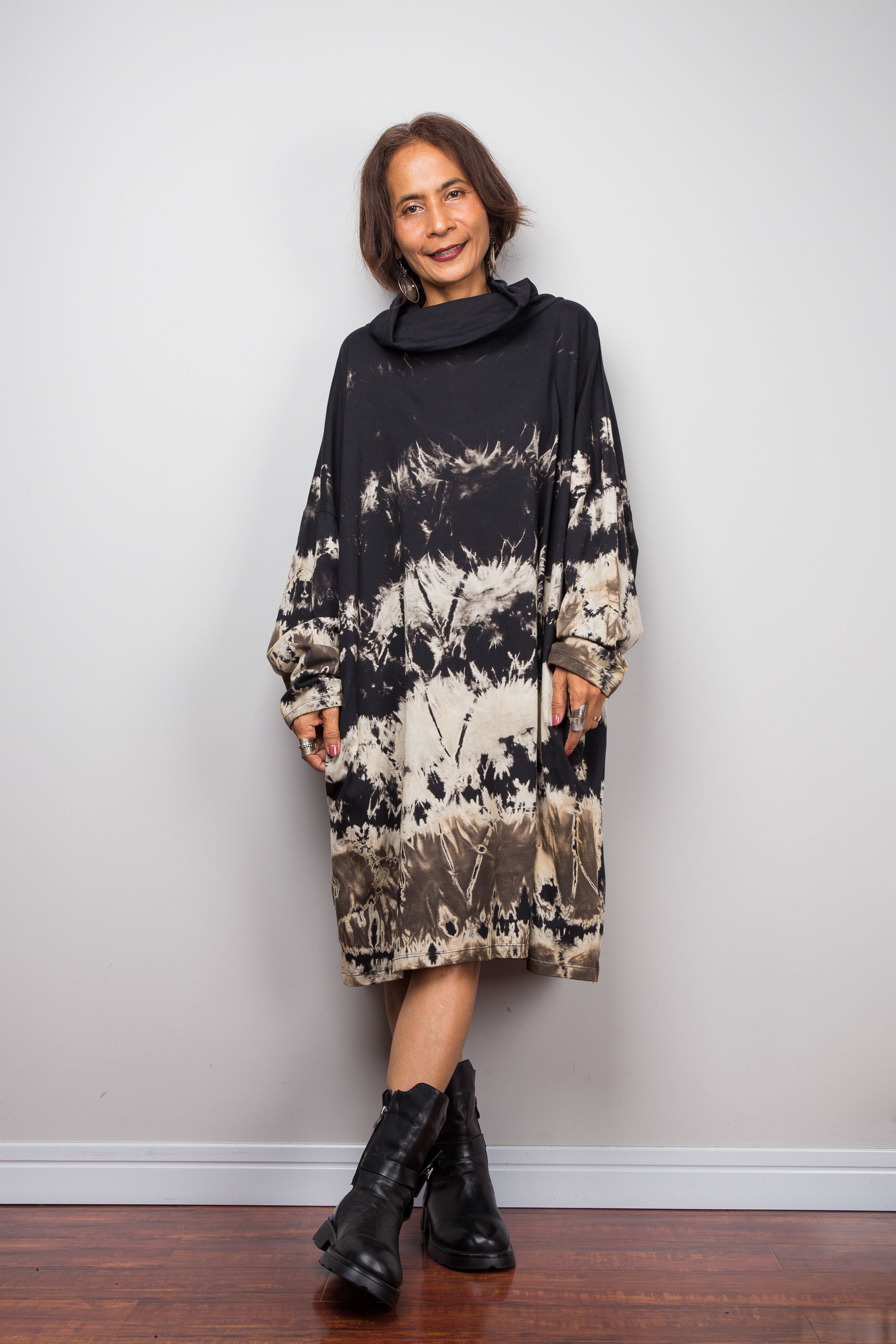 Petite women wearing an Oversized Nuichan reverse tie-dye tunic dress featuring a funnel cowl neck and abstract sand and black patterns.  Frontal view 