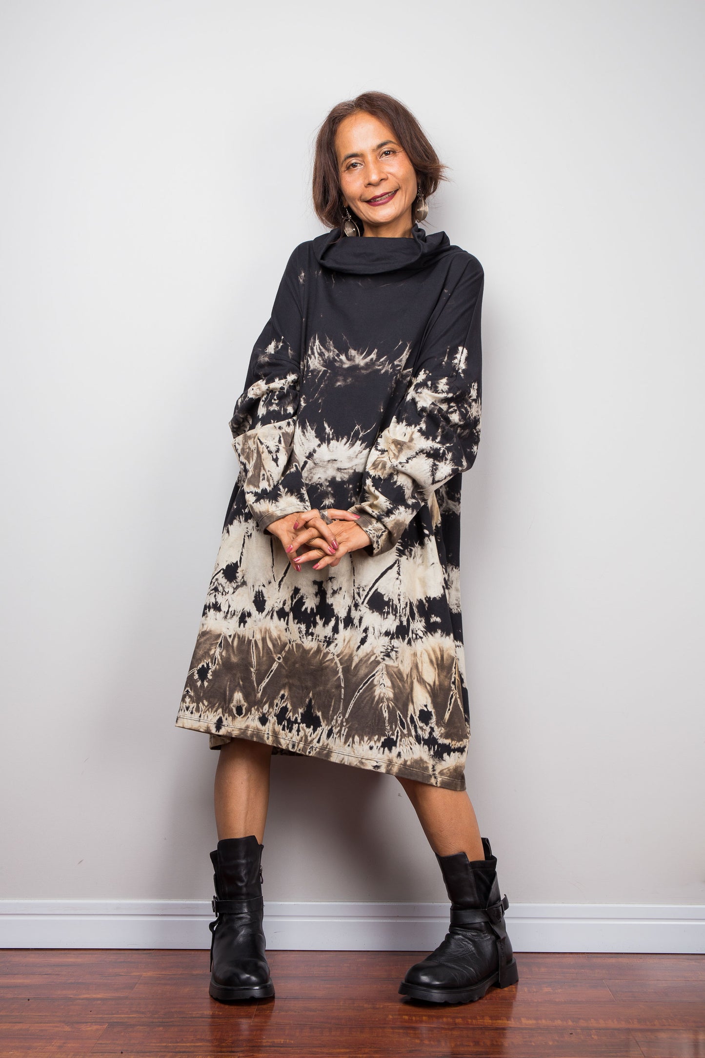 Petite women wearing an Oversized Nuichan reverse tie-dye tunic dress featuring a funnel cowl neck and abstract sand and black patterns.  Frontal view with long sleeves highlighted
