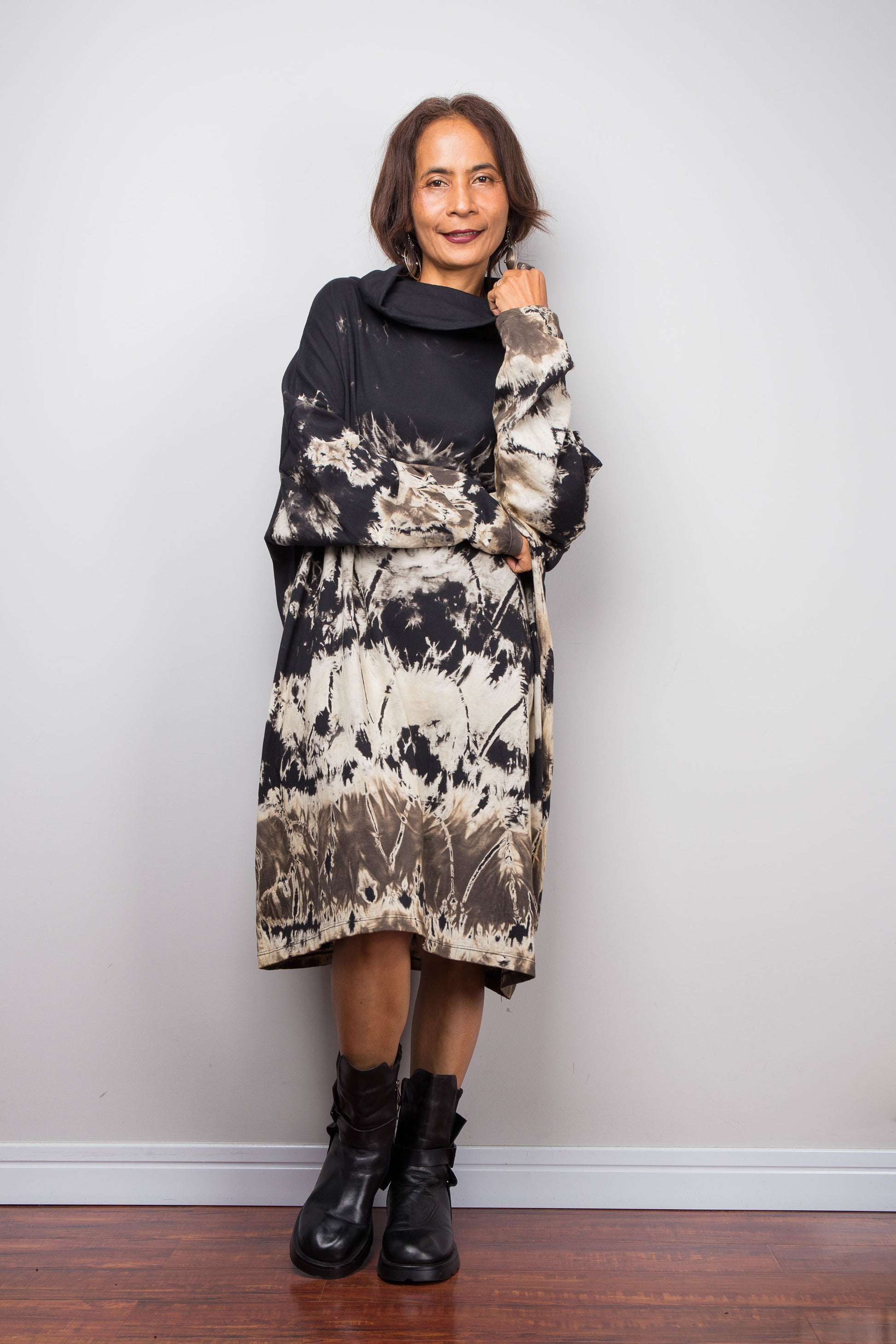 Petite women wearing an Oversized Nuichan reverse tie-dye tunic dress featuring a funnel cowl neck and abstract sand and black patterns.  Front view
