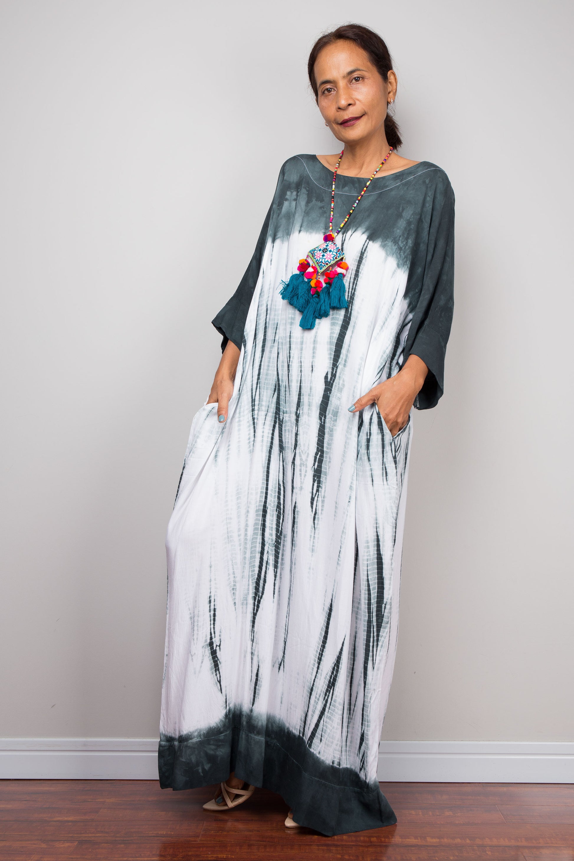 Woman wearing a long, shibori tie-dye dress with a plain background